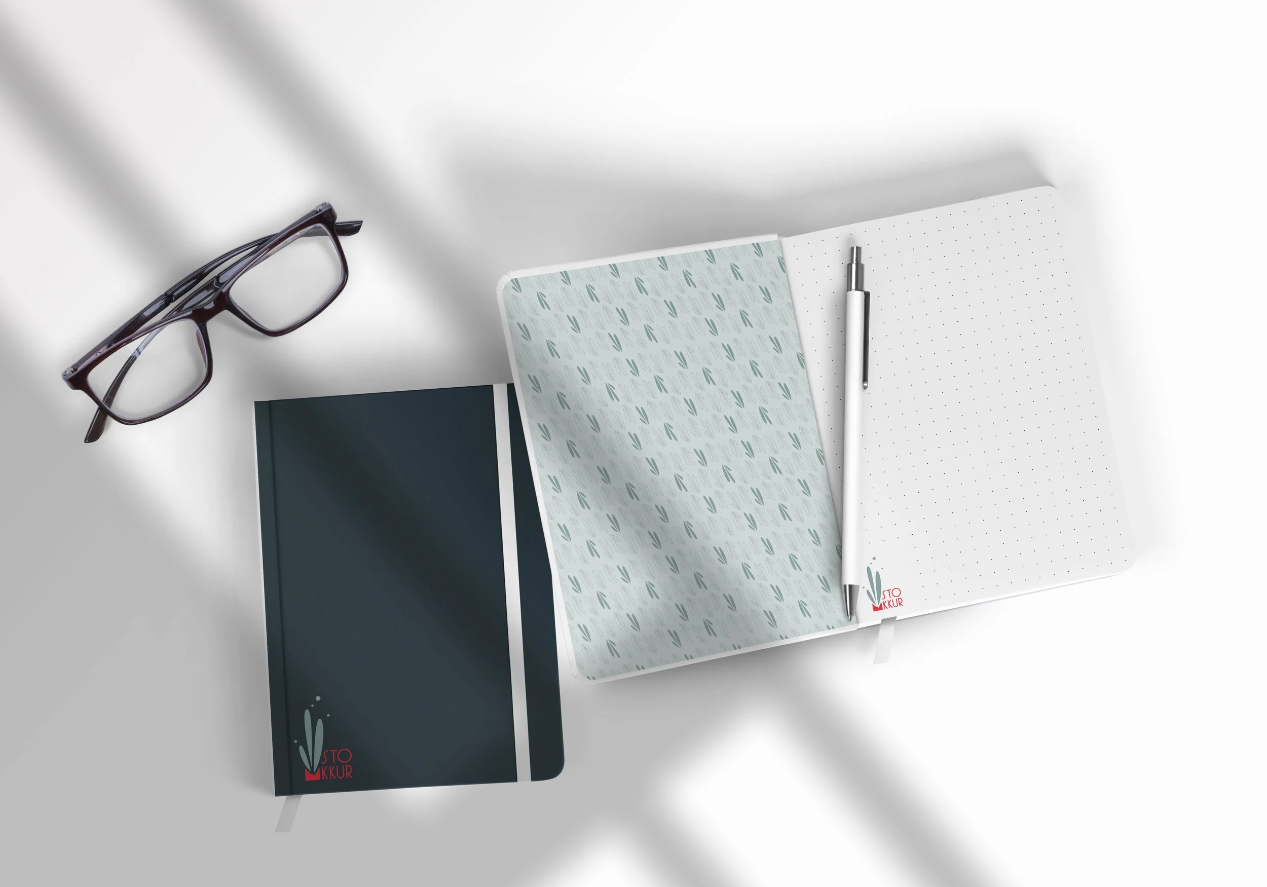 Bürobedarf mit Brille, Notizbuch, Tablet, Notizblock und Kugelschreiber auf weißem Tisch.