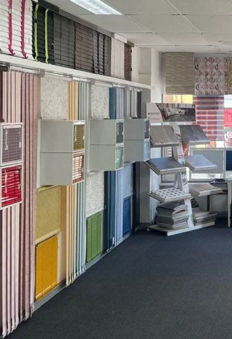 Display of fabric samples and swatches in an interior design or fabric store, organized by color and material.