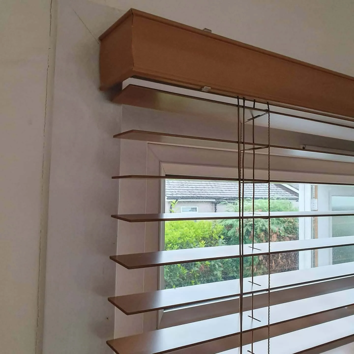 Wooden shelves mounted on a wall in front of a window with views of greenery and neighboring houses.
