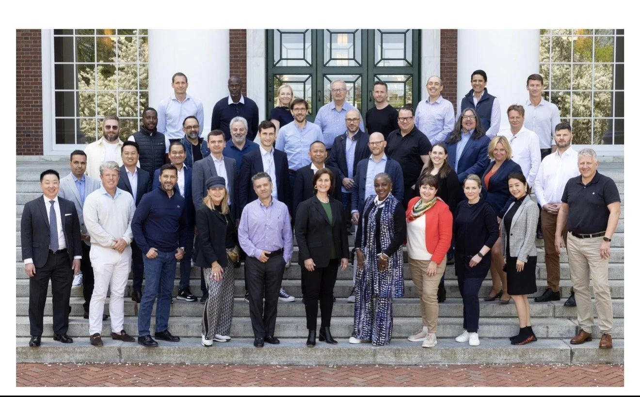Group photo of diverse business professionals on the steps outside a brick building with large windows and a green door.