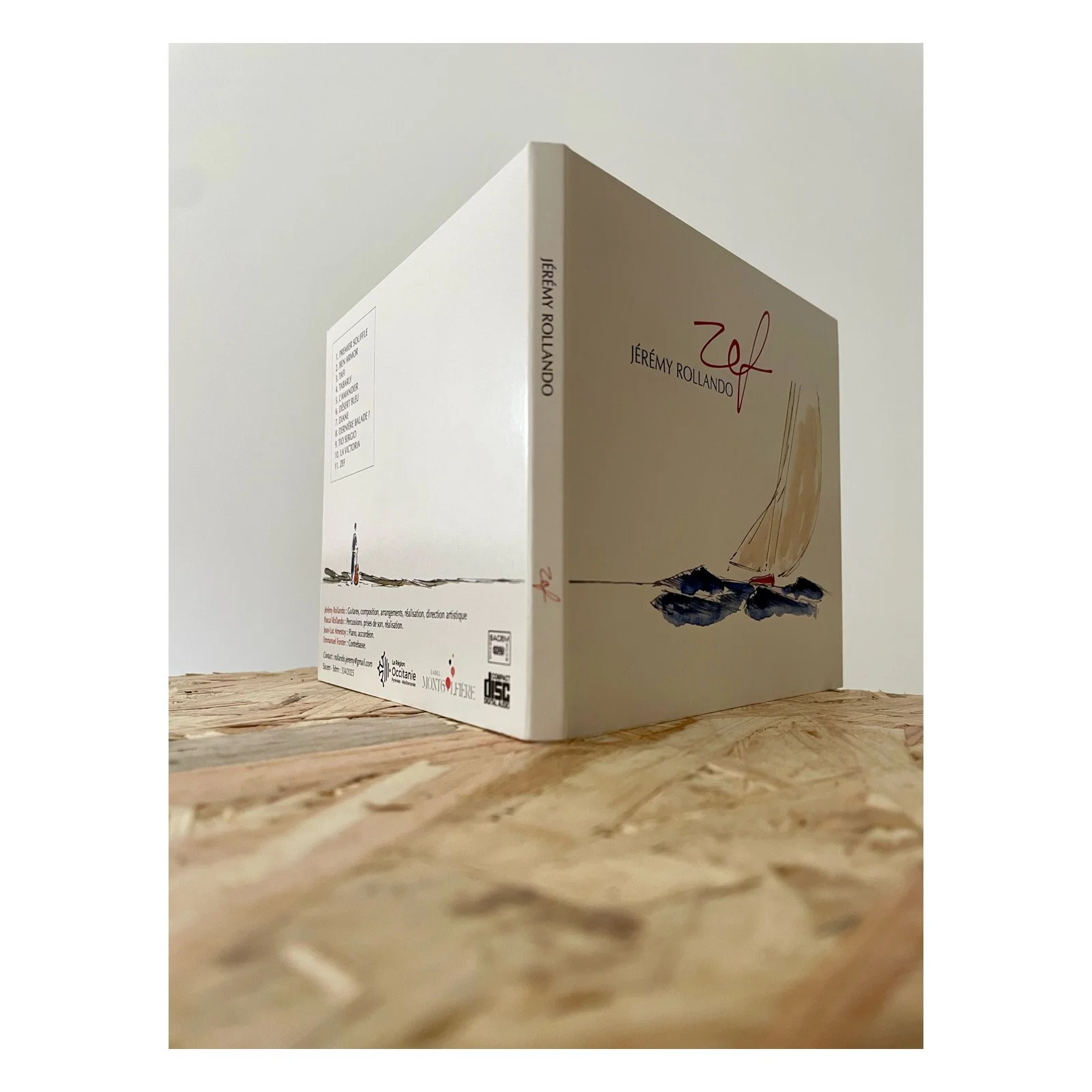 Une boîte de livre de couleur blanche avec une illustration d'un voilier sur l'eau, titré 'Jérémy Rollando'.