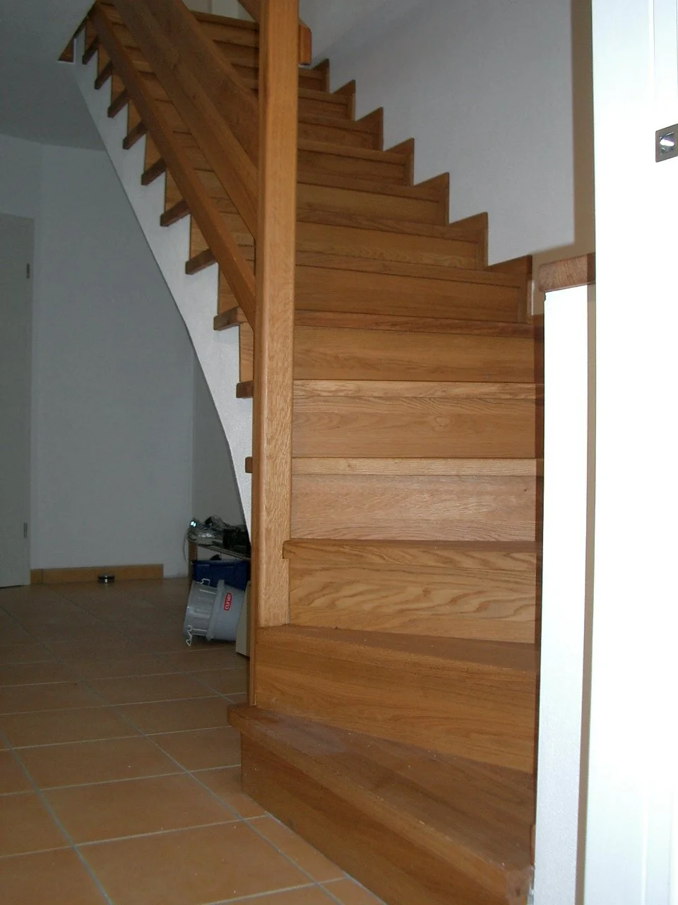 Wooden staircase with steps leading upwards in a house interior.