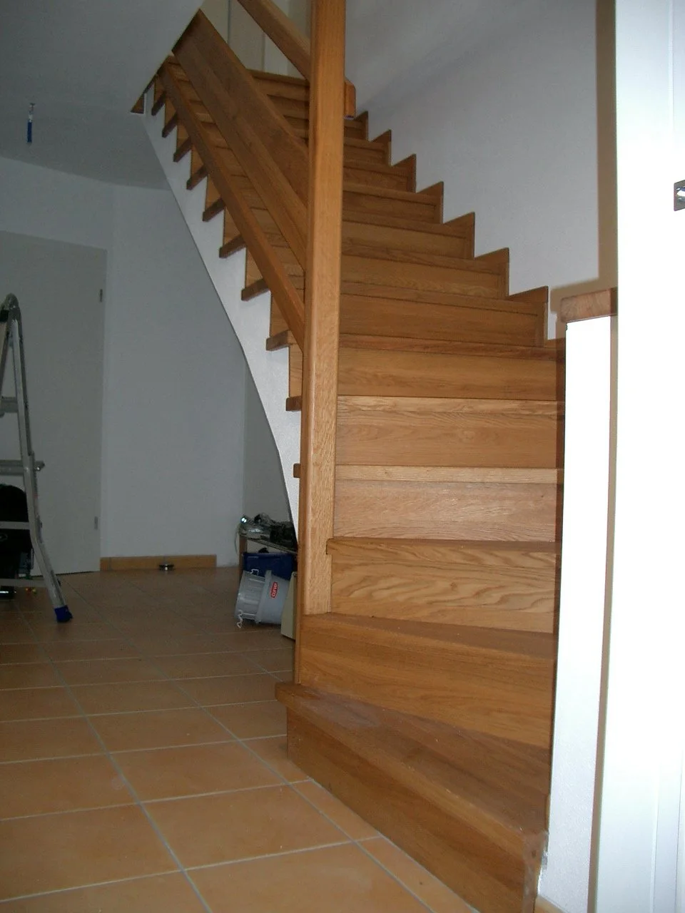 Wooden staircase inside a house with a tile floor.