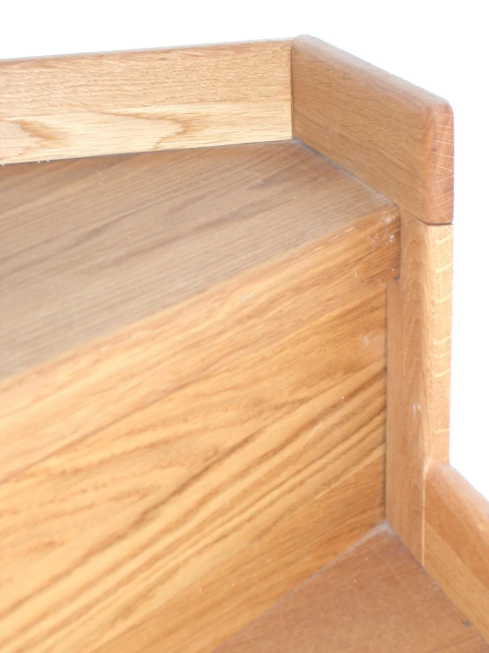 Close-up of a wooden corner shelf showing grain and rounded edges.