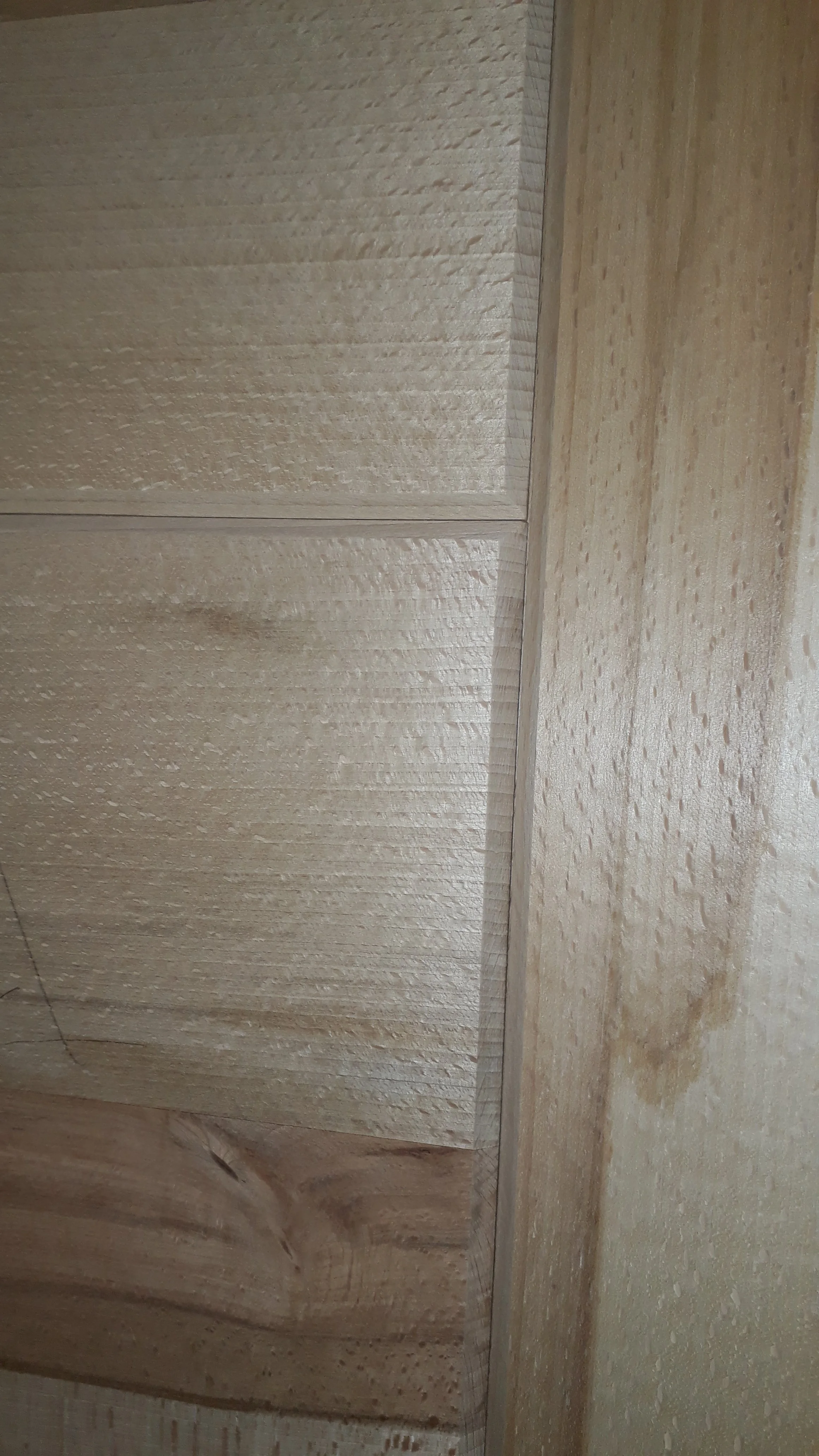 Close-up of wooden cabinetry with natural wood grain texture and a visible corner joint.