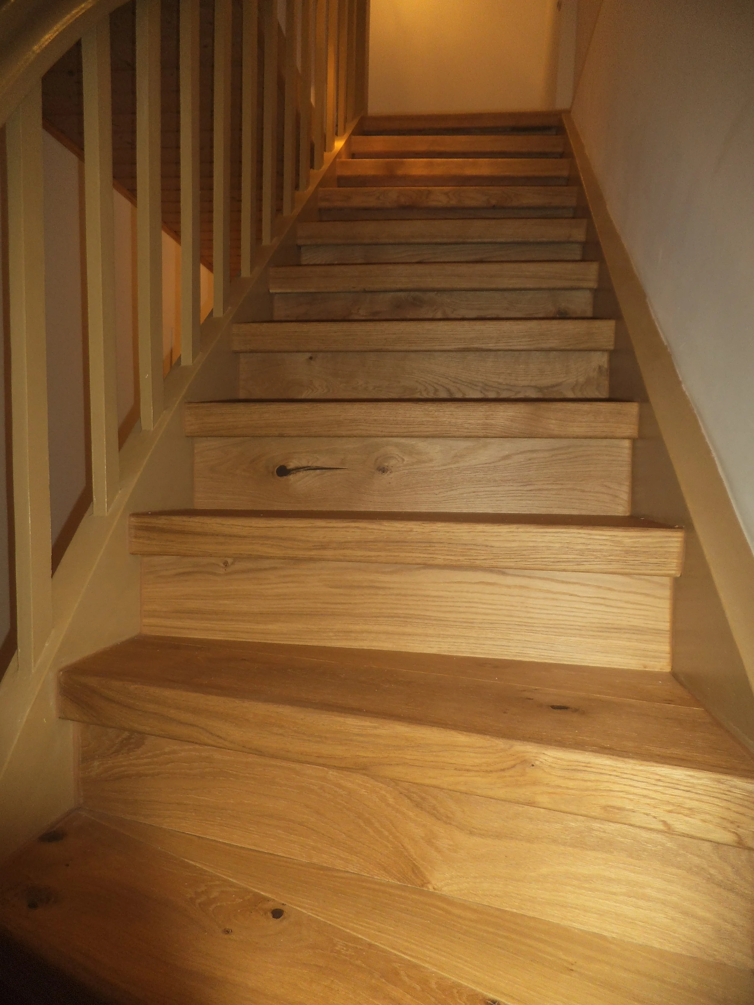 Wooden stairs with a curved design and a railing on the left side.