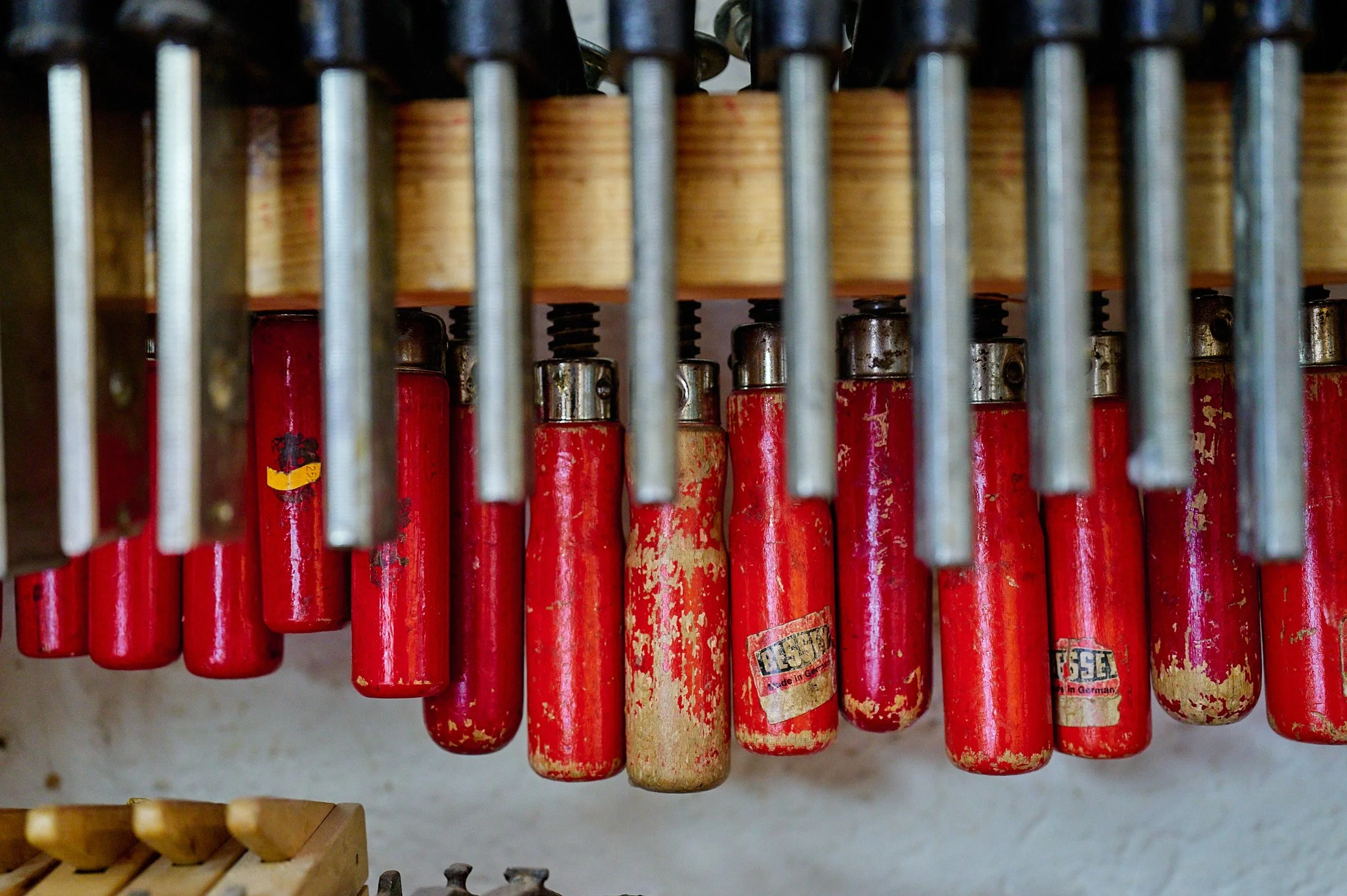 A row of old, red, used fire extinguishers hanging on a wall.