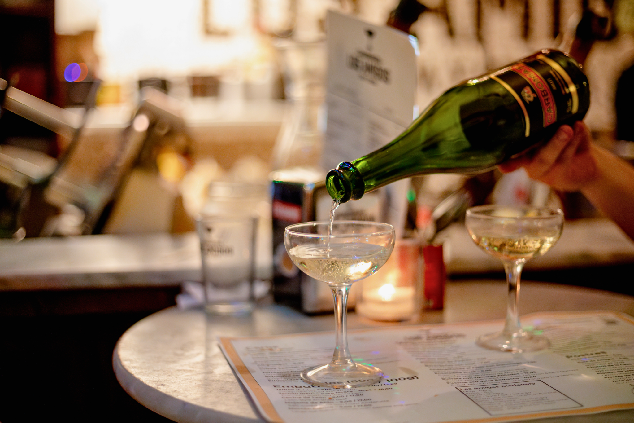Person pouring cava into a glass at a bar or restaurant.