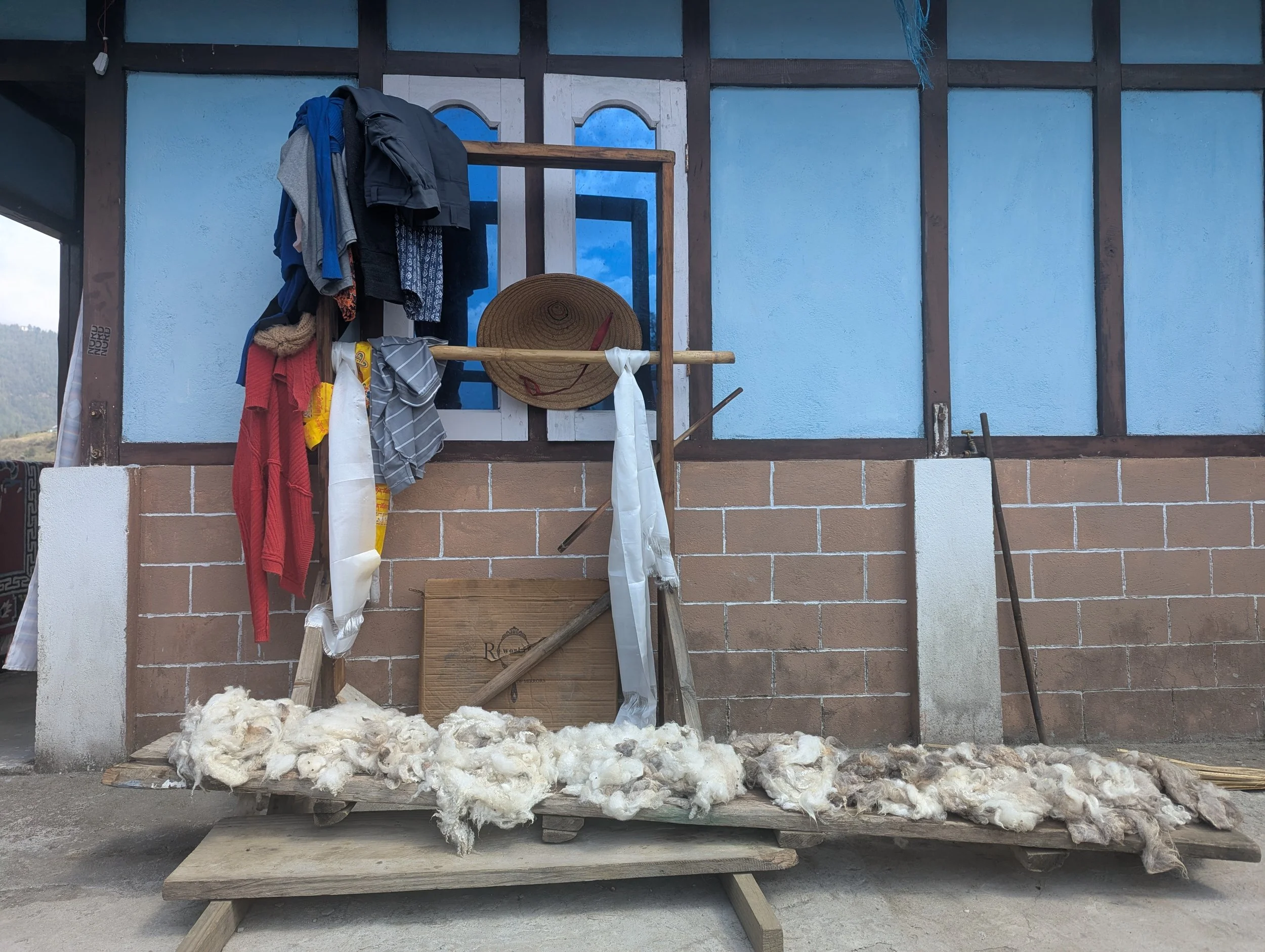 Raw yak wool laid out to dry on a wooden rack outside a traditional Monpa home in Arunachal Pradesh, documenting craft knowledge during the Norbu Governance Futures field research by Lagori Collective.