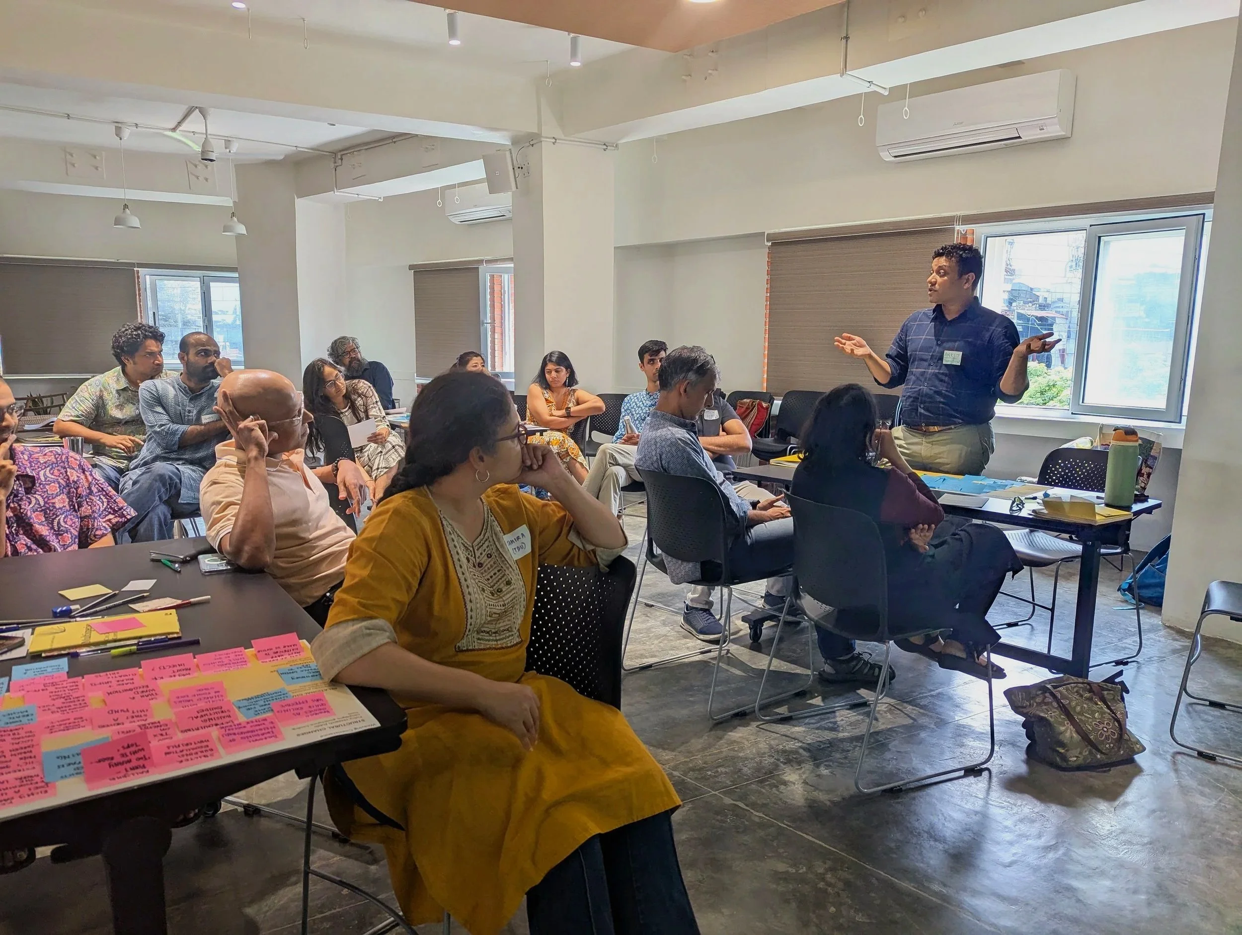 Facilitated discussion during the Weaving Co-Existence convening by Lagori Collective with practitioners from ecology, law, design, and research gathered around tables covered in scenario cards.