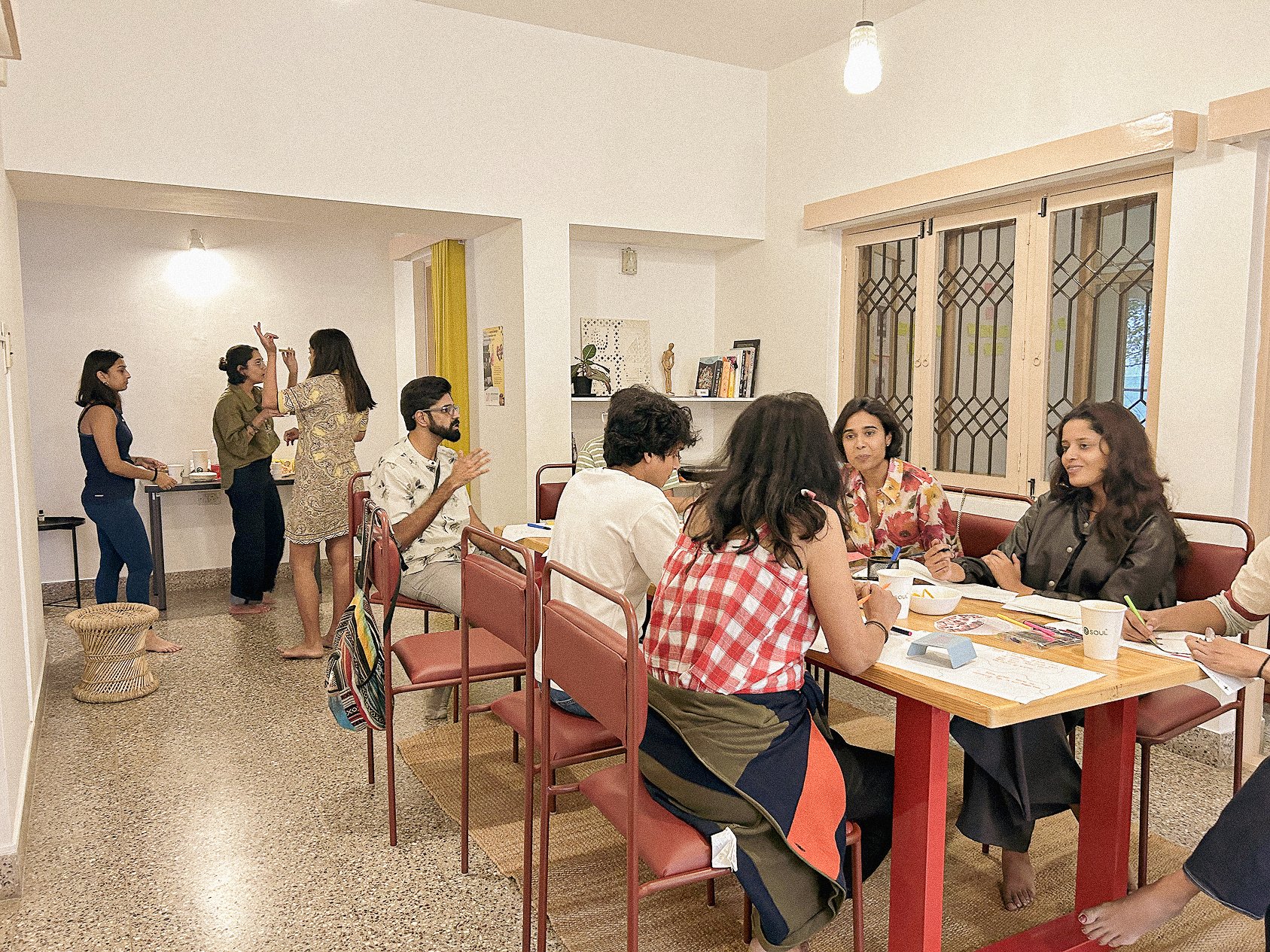 Practitioners gathered for a workshop session at Lagori Collective's cooperative community workspace in Bengaluru, with some working at tables and others in conversation across the room.