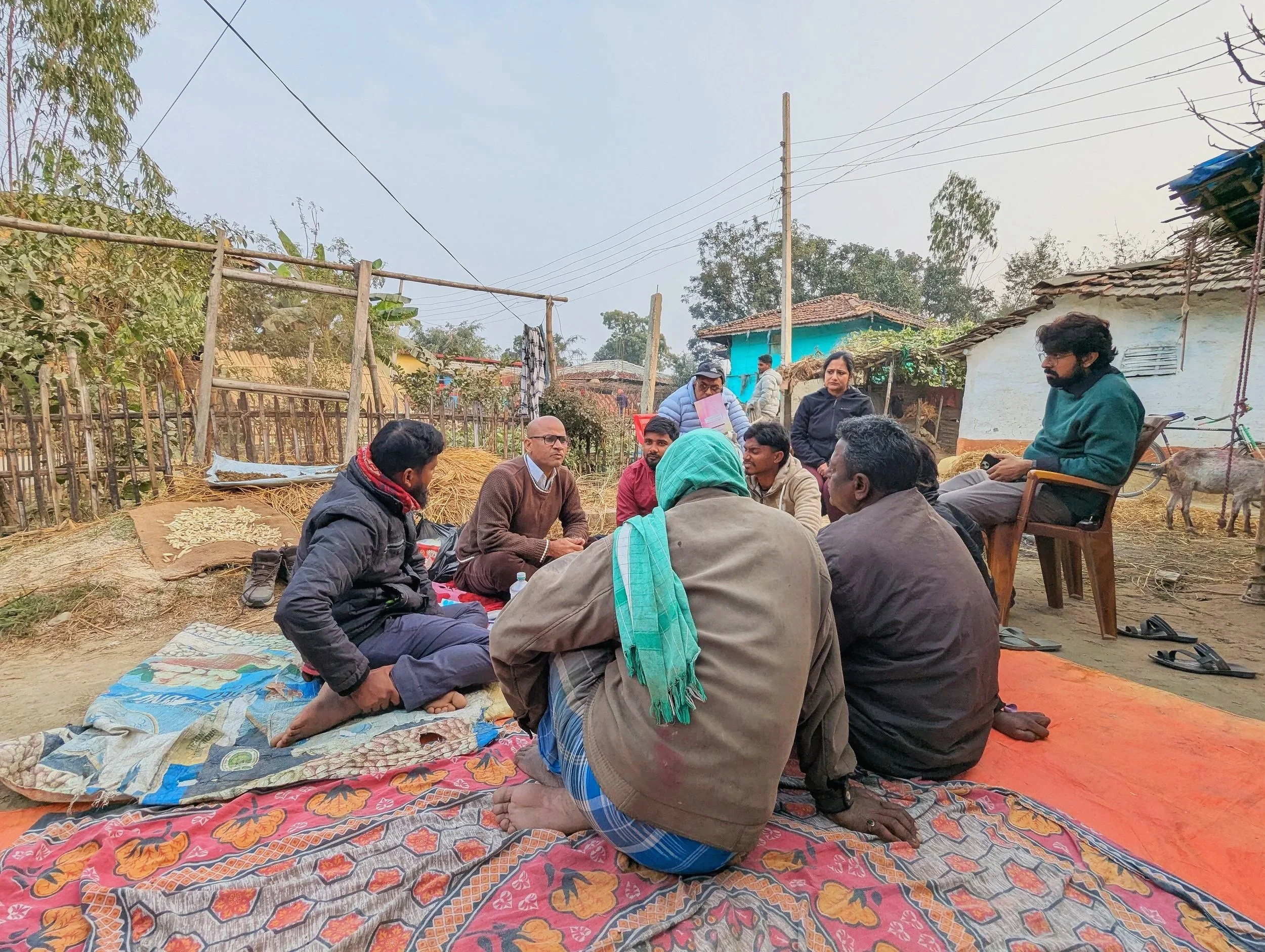 Men seated outdoors in a village in the Terai region of Nepal during a participatory research session on caregiving and nutrition norms, conducted by Lagori Collective with USAID Integrated Nutrition and Helen Keller International.