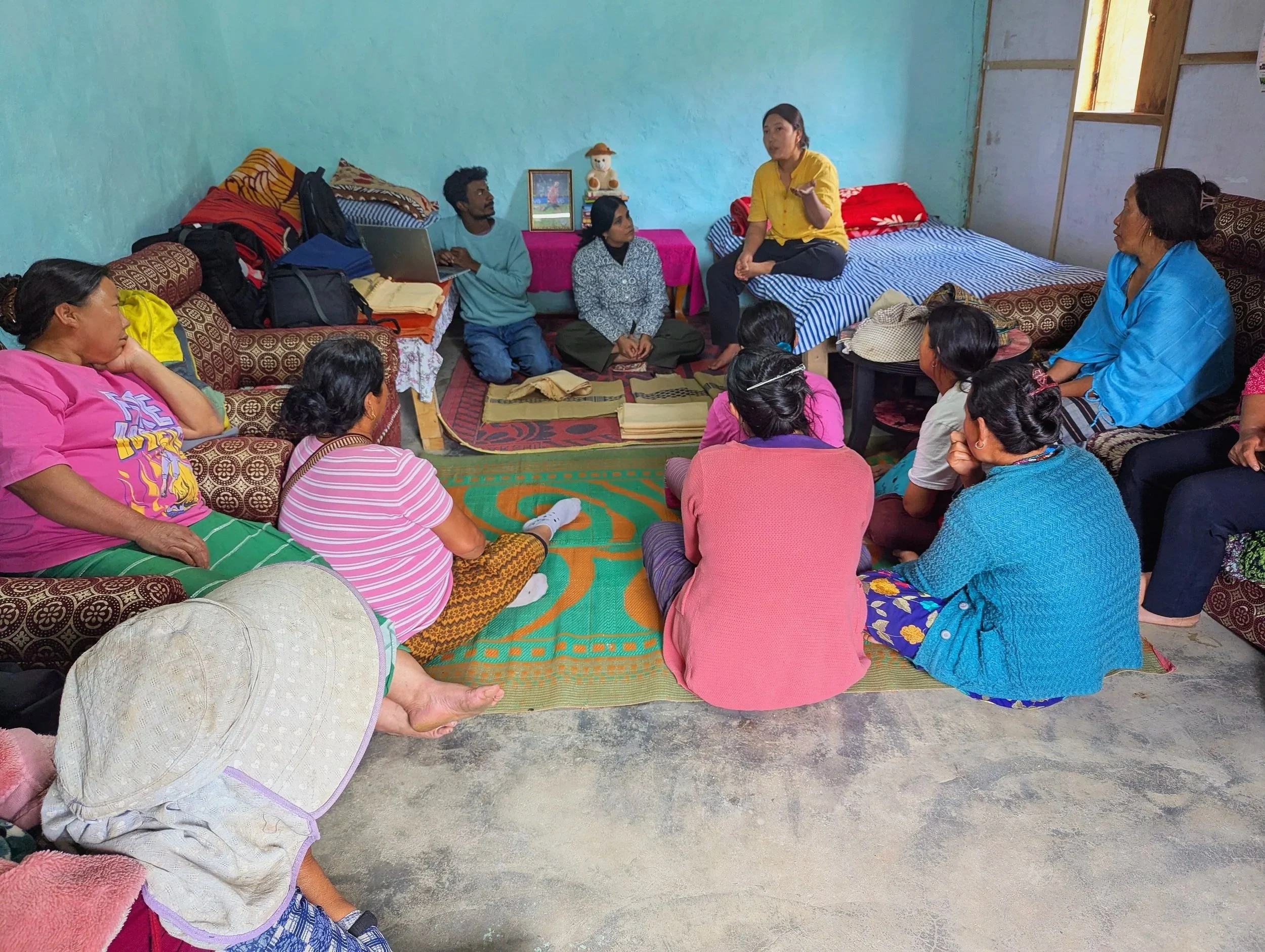 Participatory community session with Brokpa women and Lagori Collective researchers seated on the floor of a home in Arunachal Pradesh, co-designing governance for the Norbu craft collective with It's All Folk.