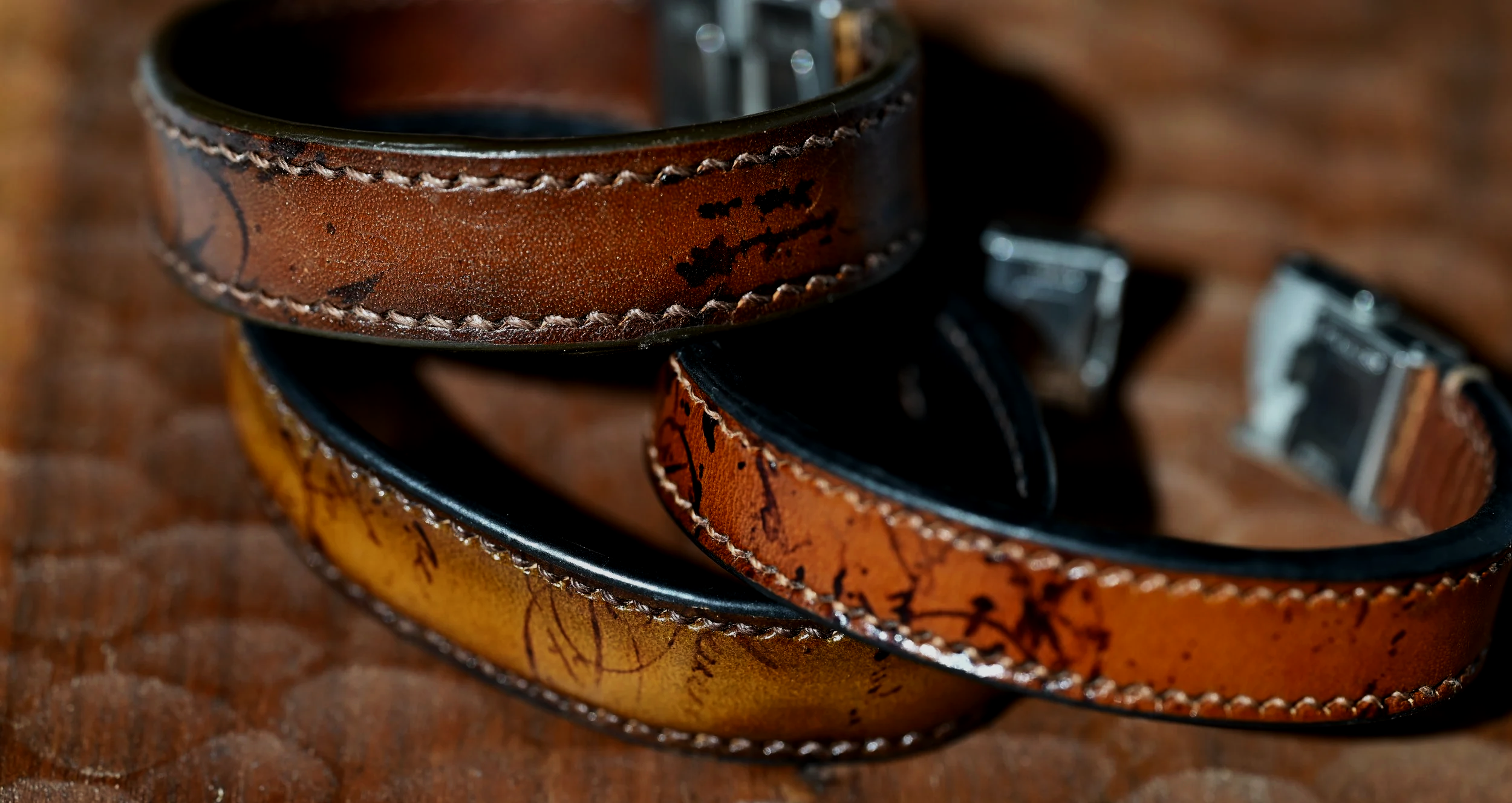 3 bracelets en cuir tanné végétal patiné sont super posés et posés sur du bois