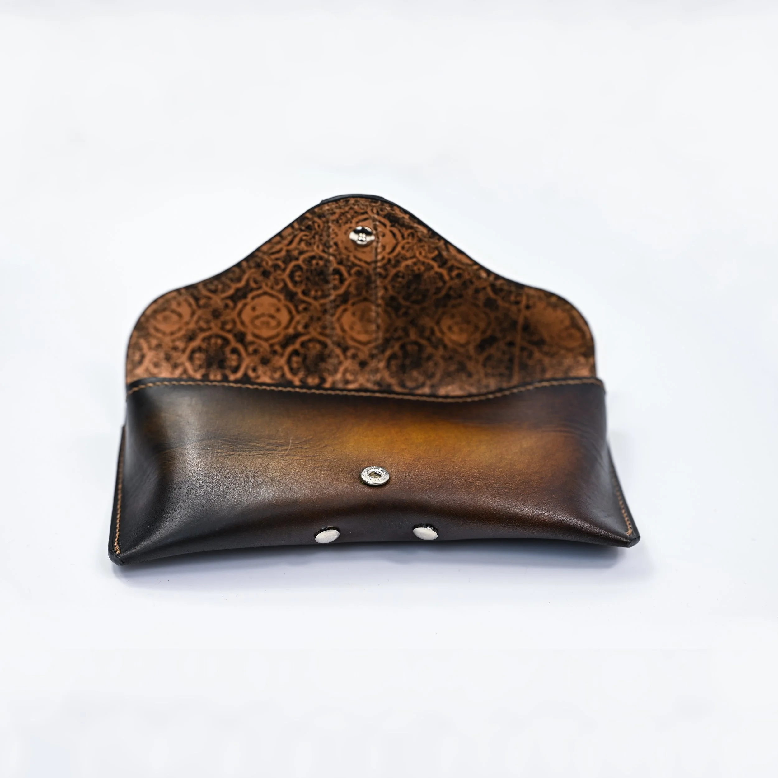 Une pochette en cuir ouverte, avec un intérieur avec motif orangé et marron.