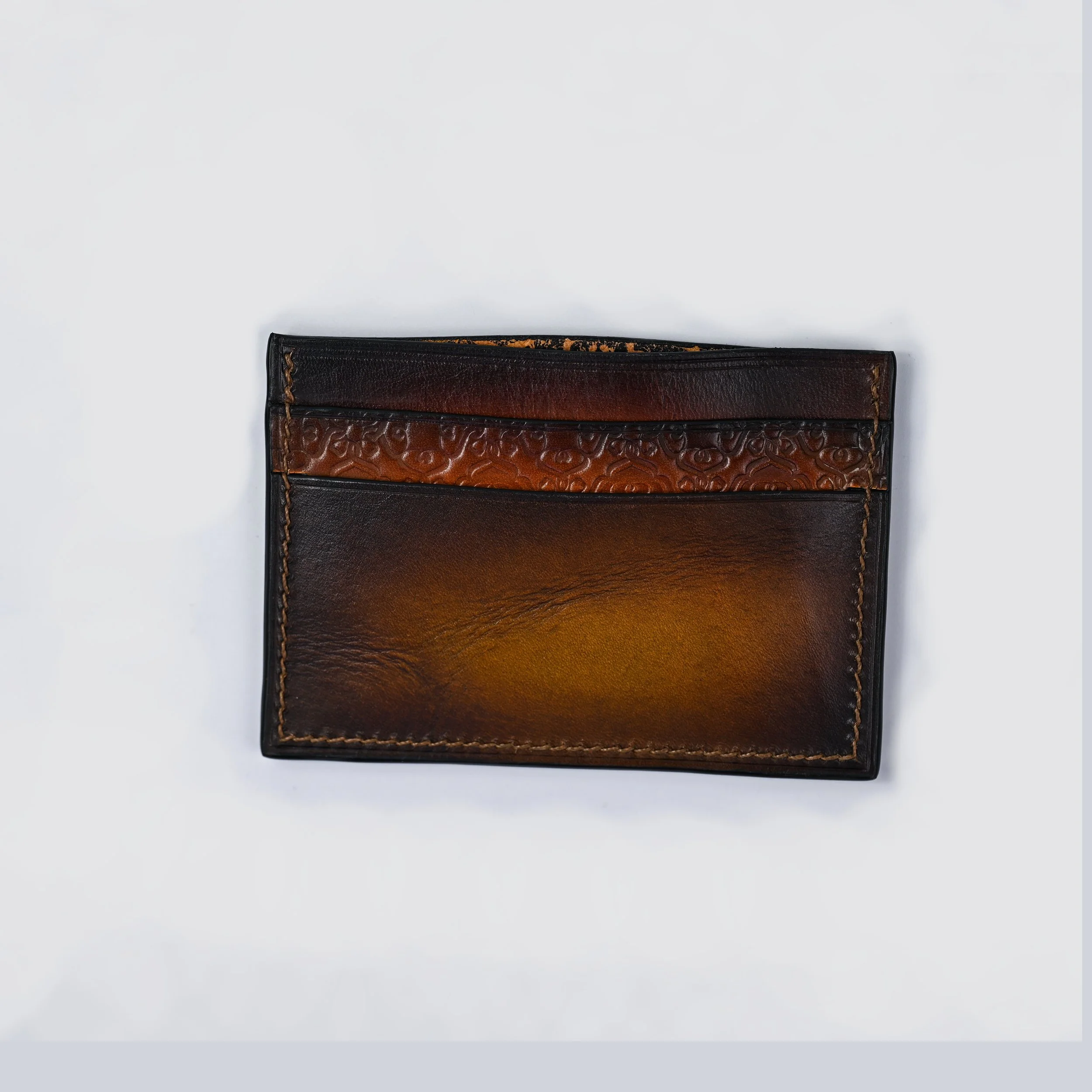 Porte-monnaie en cuir marron et noir avec détails en relief.