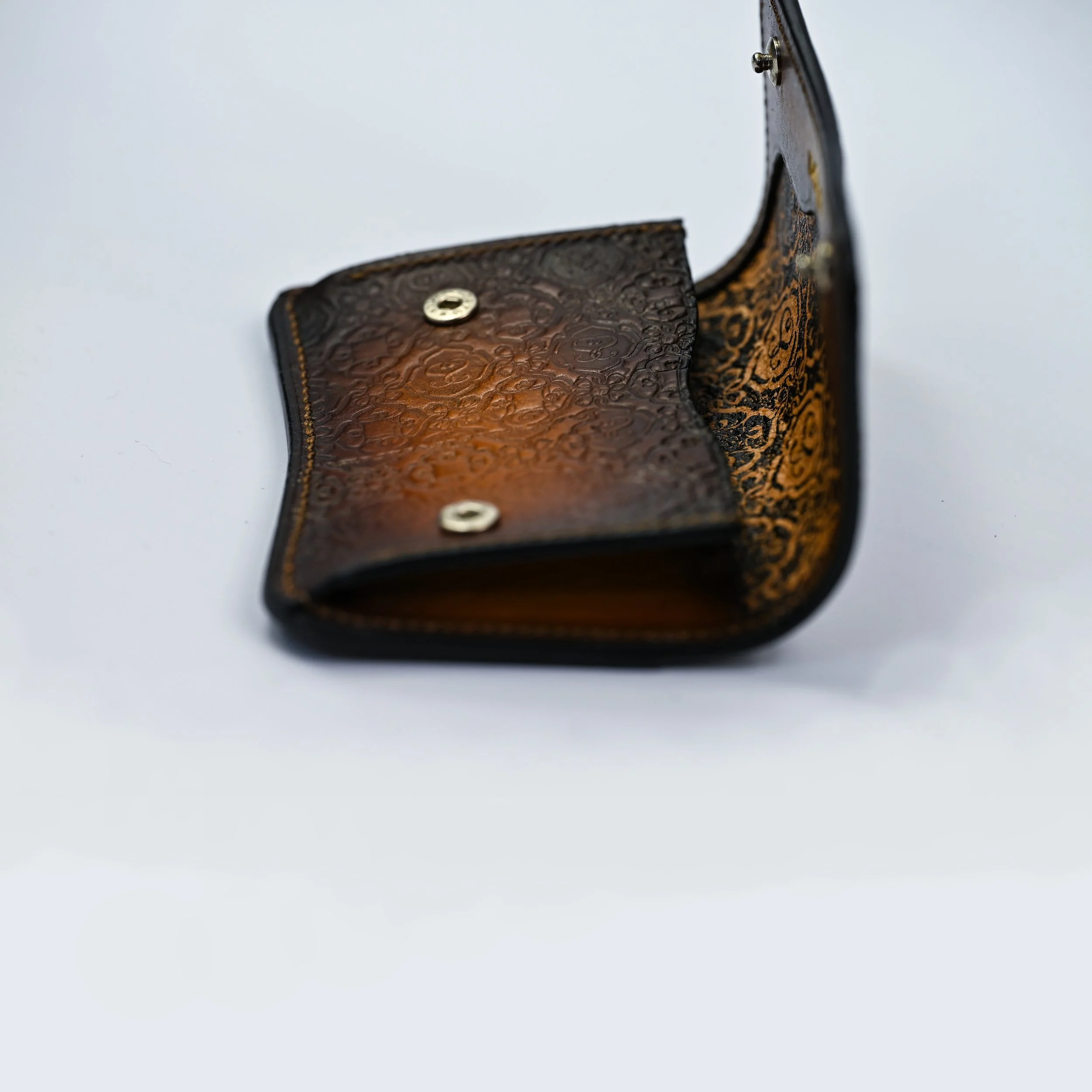 Portefeuille en cuir ouvert, avec intérieur orange et motifs floraux noirs.