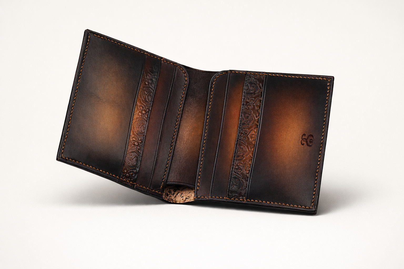 Portefeuille en cuir marron foncé avec des motifs gravés, ouvert sur un fond blanc.