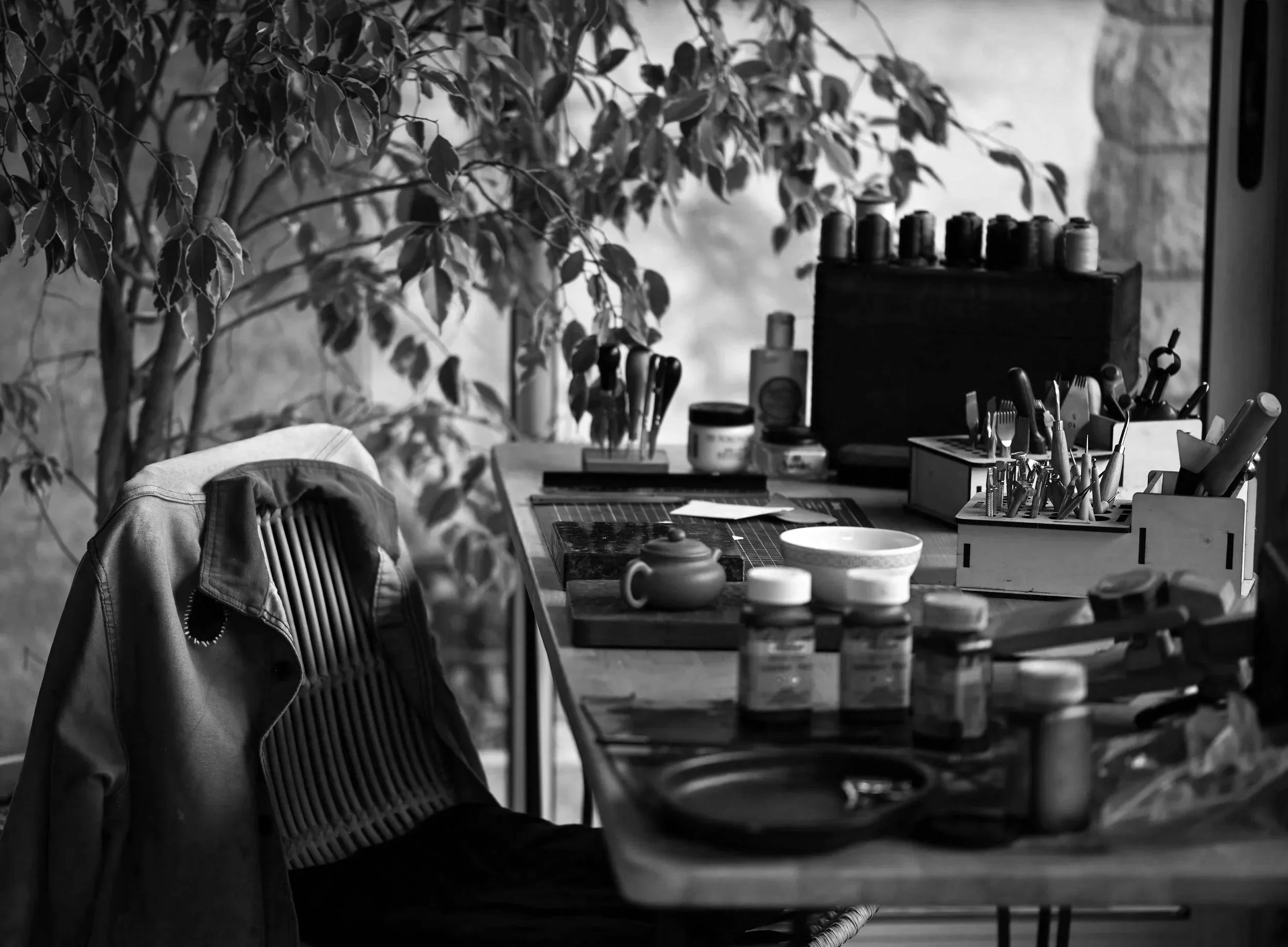 Un espace de travail de maroquinier avec divers outils et pots de teinture et une chaise avec une veste de travail