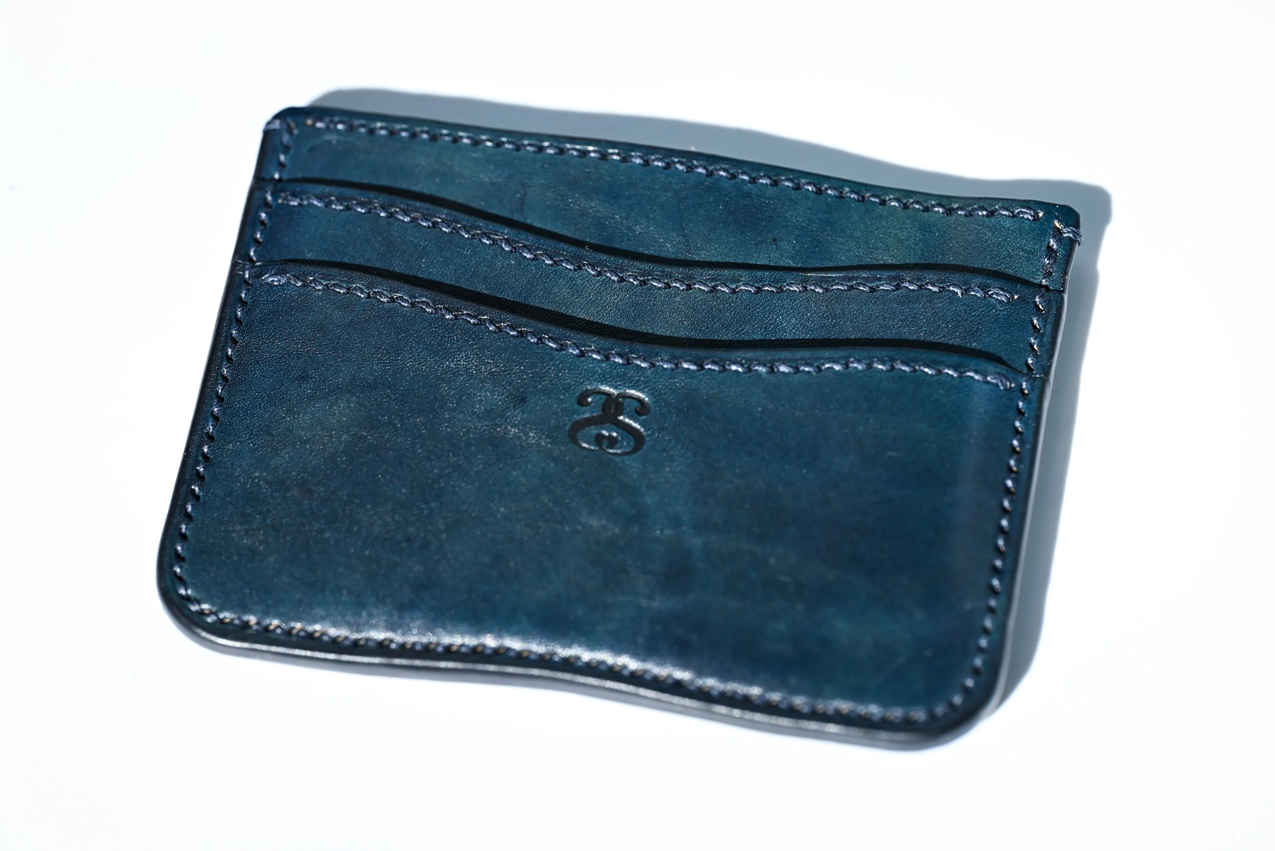 Portefeuille bleu en cuir avec 2 pochettes pour cartes, posé sur fond blanc.