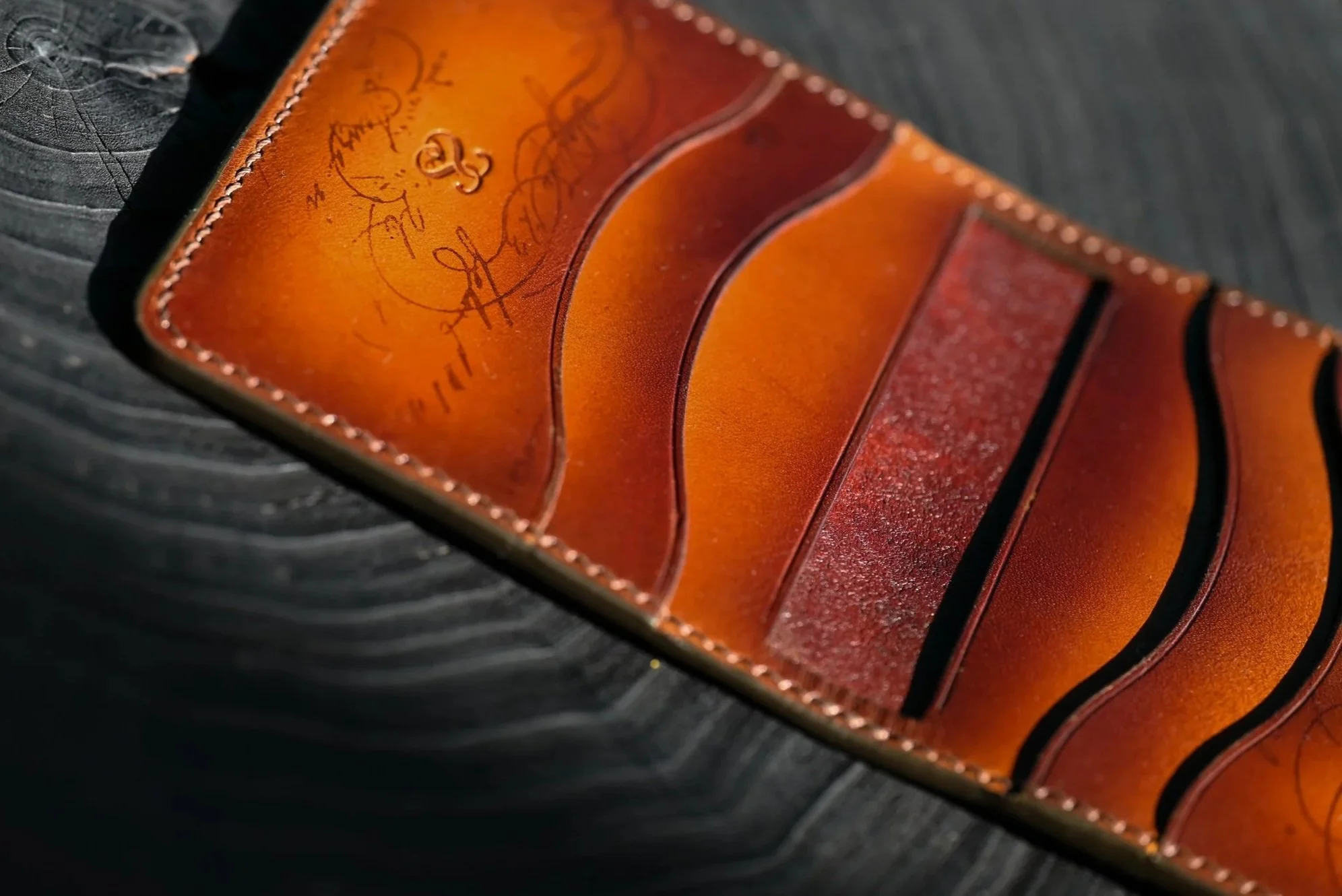 Porte-cartes en cuir tanné végétal patiné et posé sur une surface en bois noir