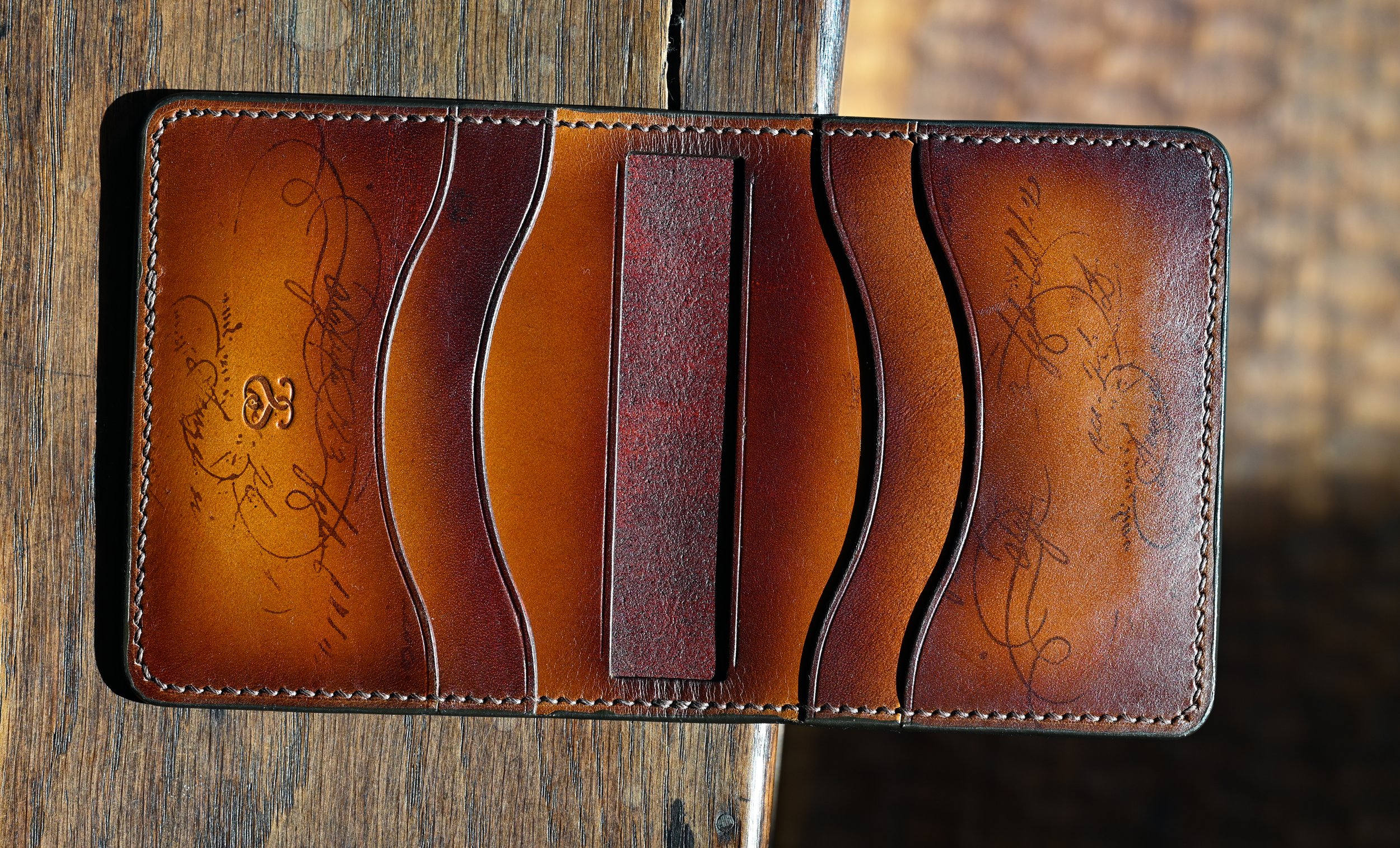 Un porte-cartes en cuir marron avec des signatures, placé sur une surface en bois.