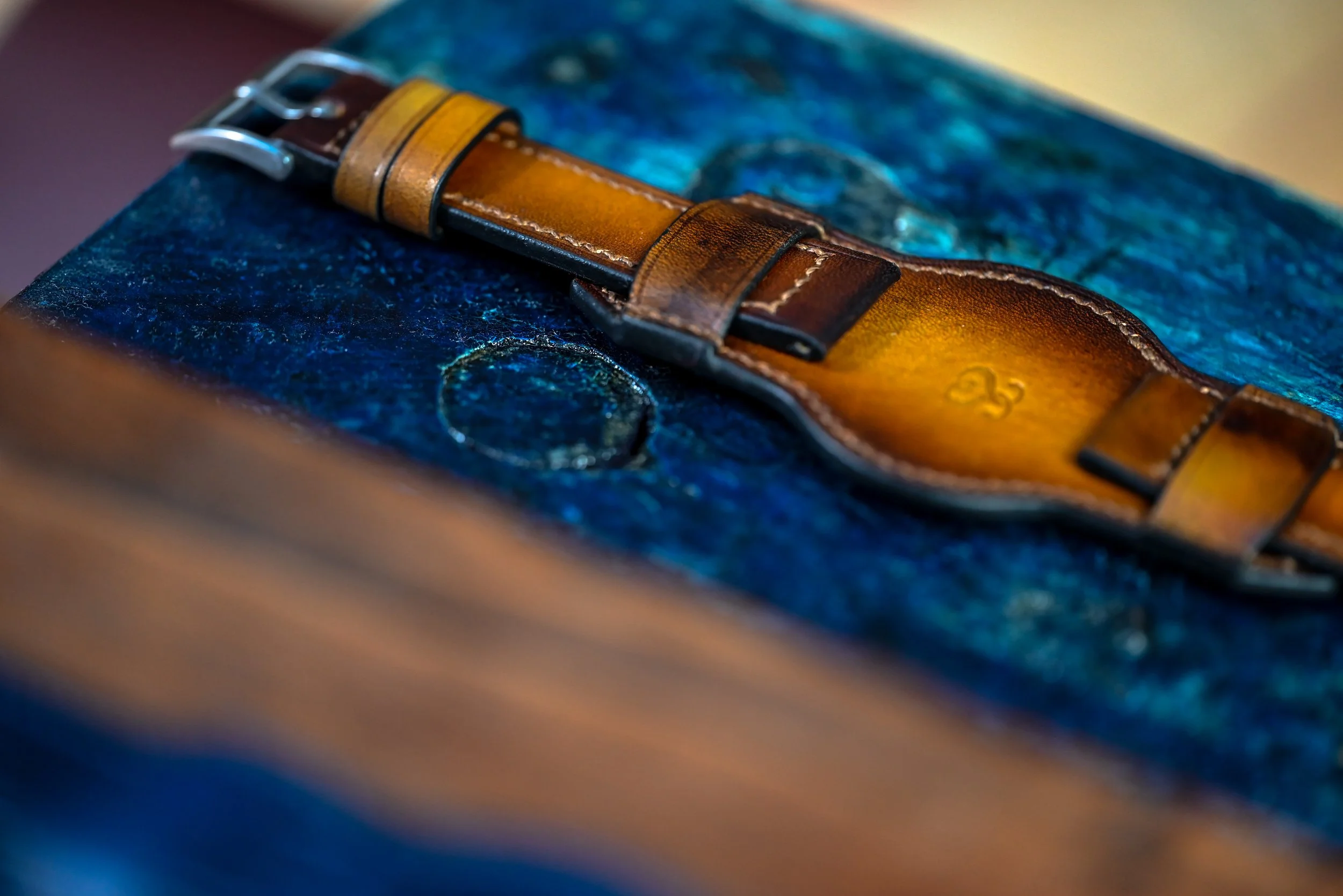 Ceinture en cuir marron posée sur un livre avec une couverture bleue.