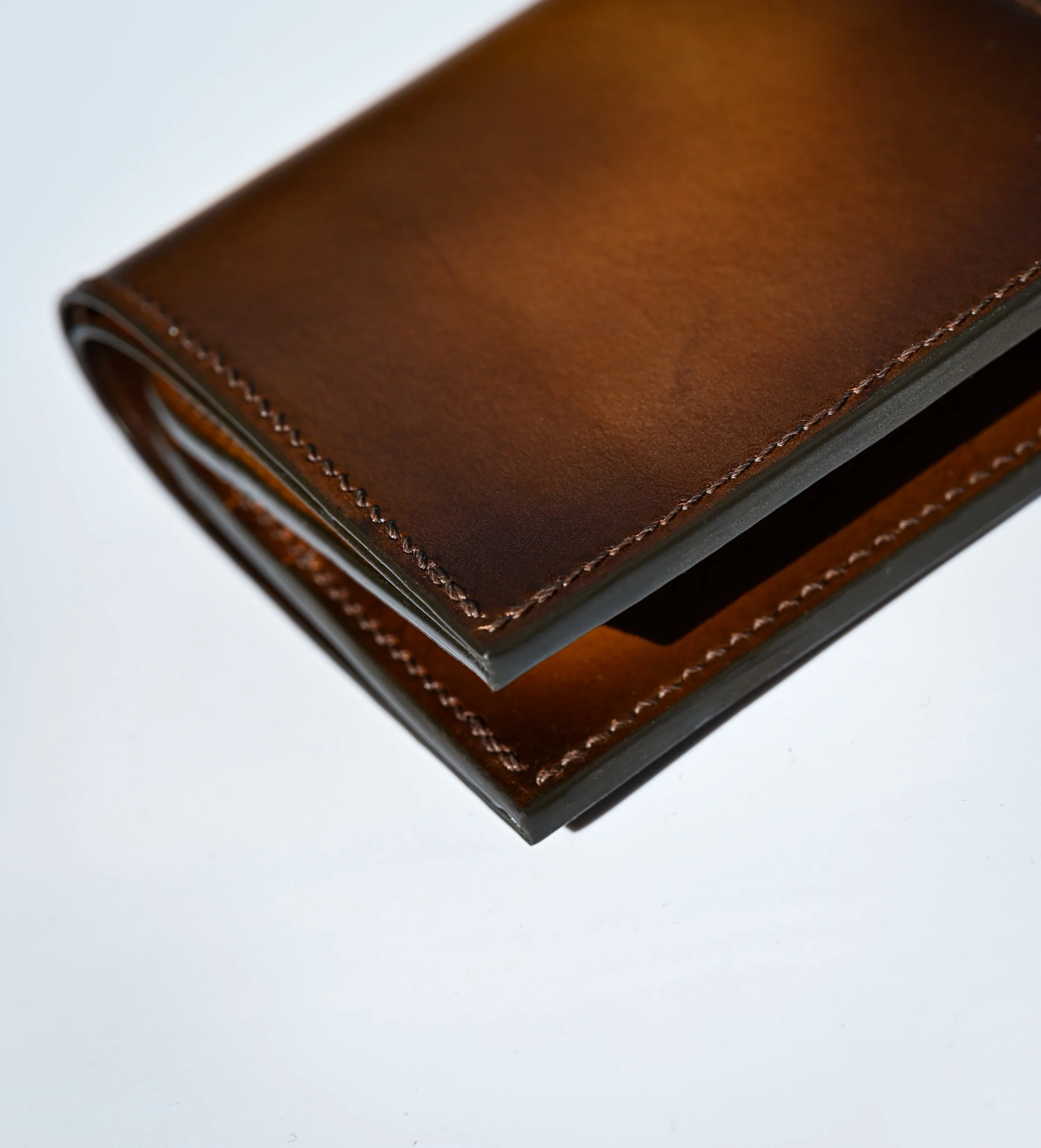 Détail d'un portefeuille patiné à la main avec des nuances de marron et une couture point sellier