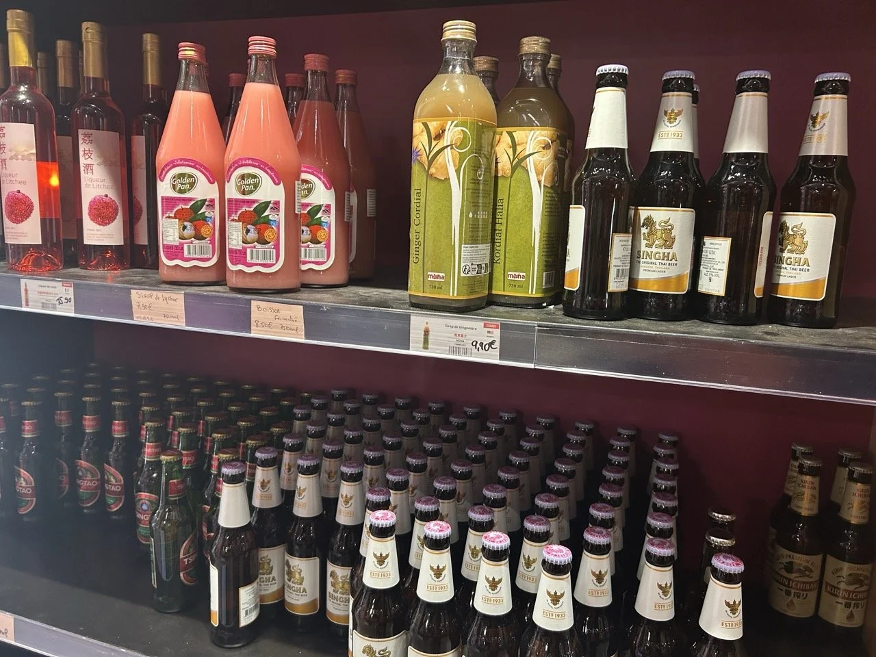 Bouteilles de boissons non alcoolisées et alcoolisées sur des étagères dans un supermarché, avec des étiquettes en français.