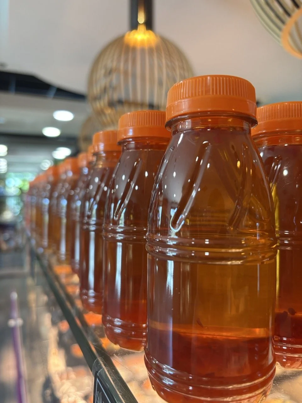 Ligne de bouteilles en plastique transparentes avec liquide orange, dans un magasin