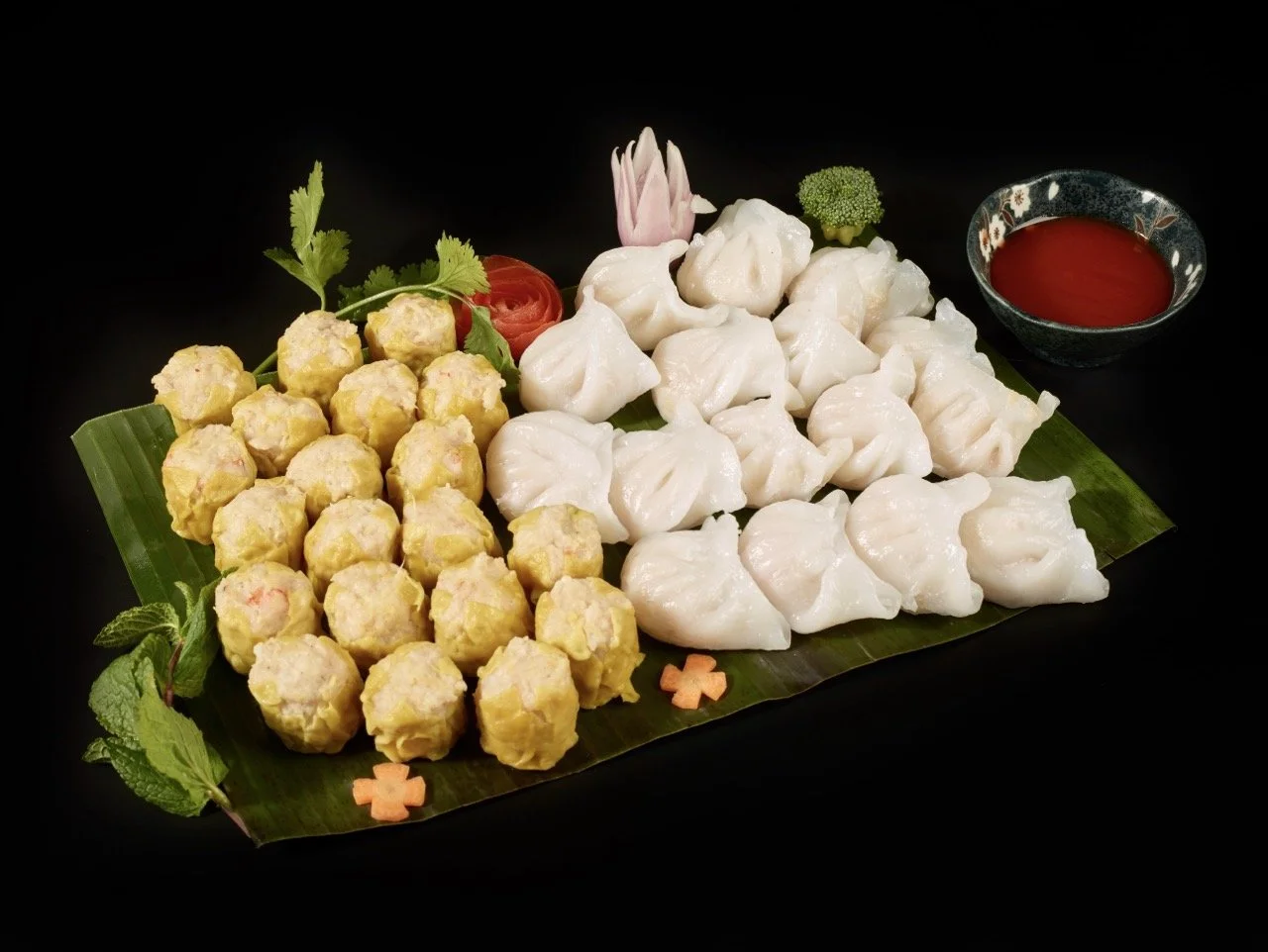 Plate de raviolis et boulettes de crevettes avec sauce rouge, garniture de plantes et fleurs