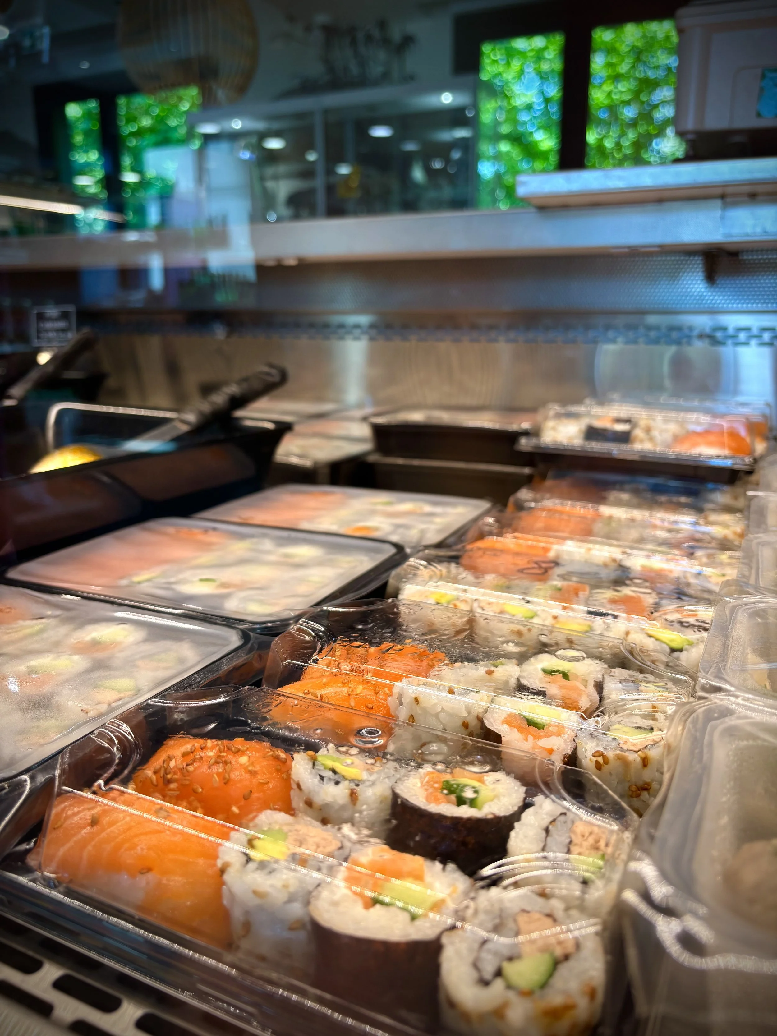 Assortiment de sushis dans une boîte en plastique, avec différentes variétés de poisson et de légumes, dans un restaurant.
