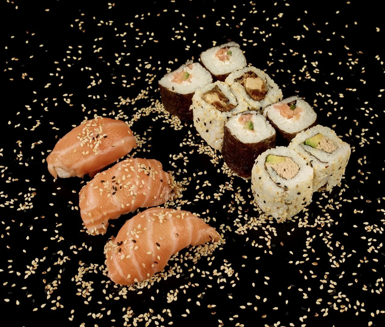 Assortiment de sushis avec saumon et rouleaux d'algues, décoré de graines de sésame sur un fond noir.