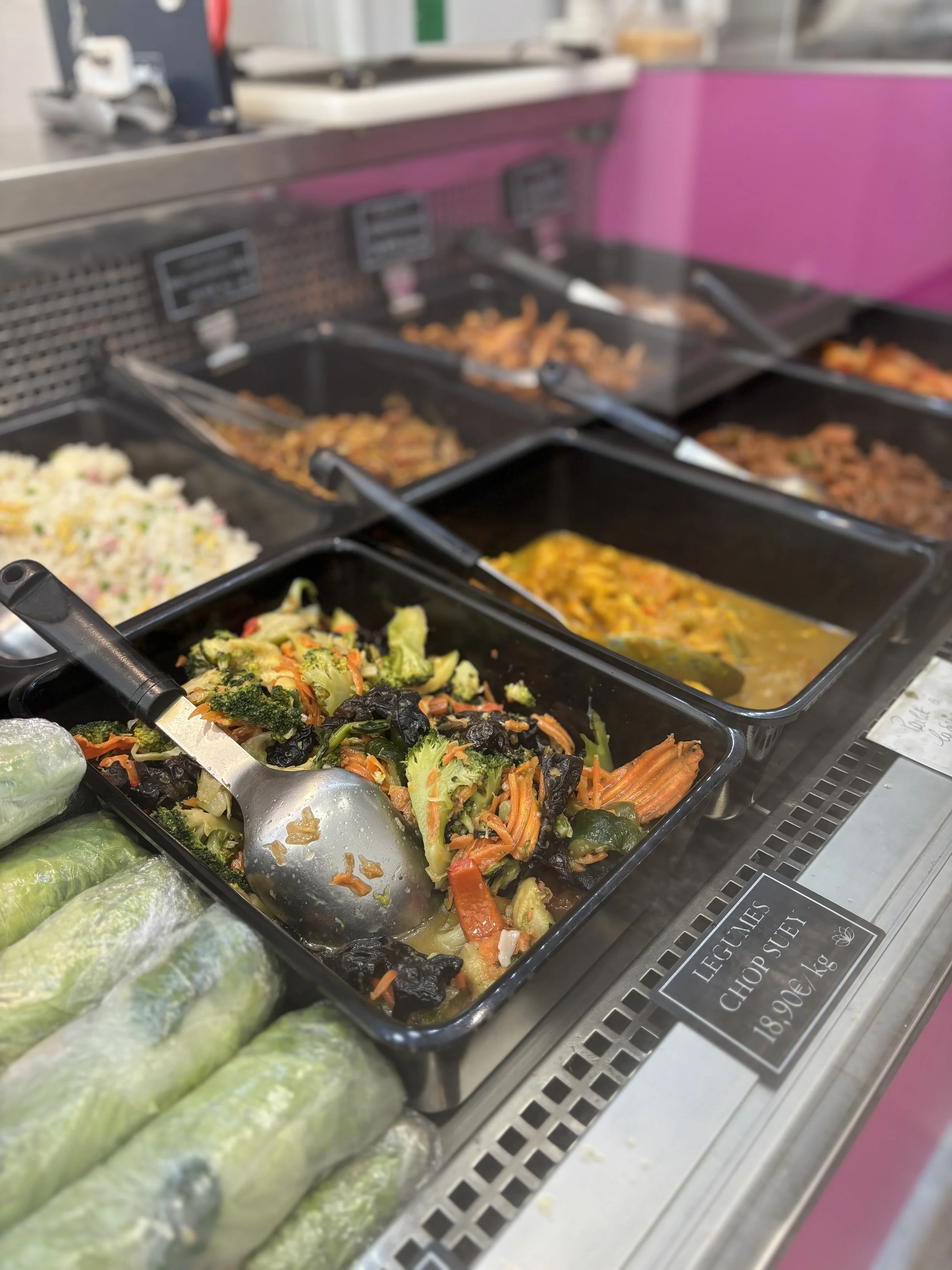 Plat de légumes sautés dans un comptoir de buffet. Avec des rouleaux de printemps en premier plan.