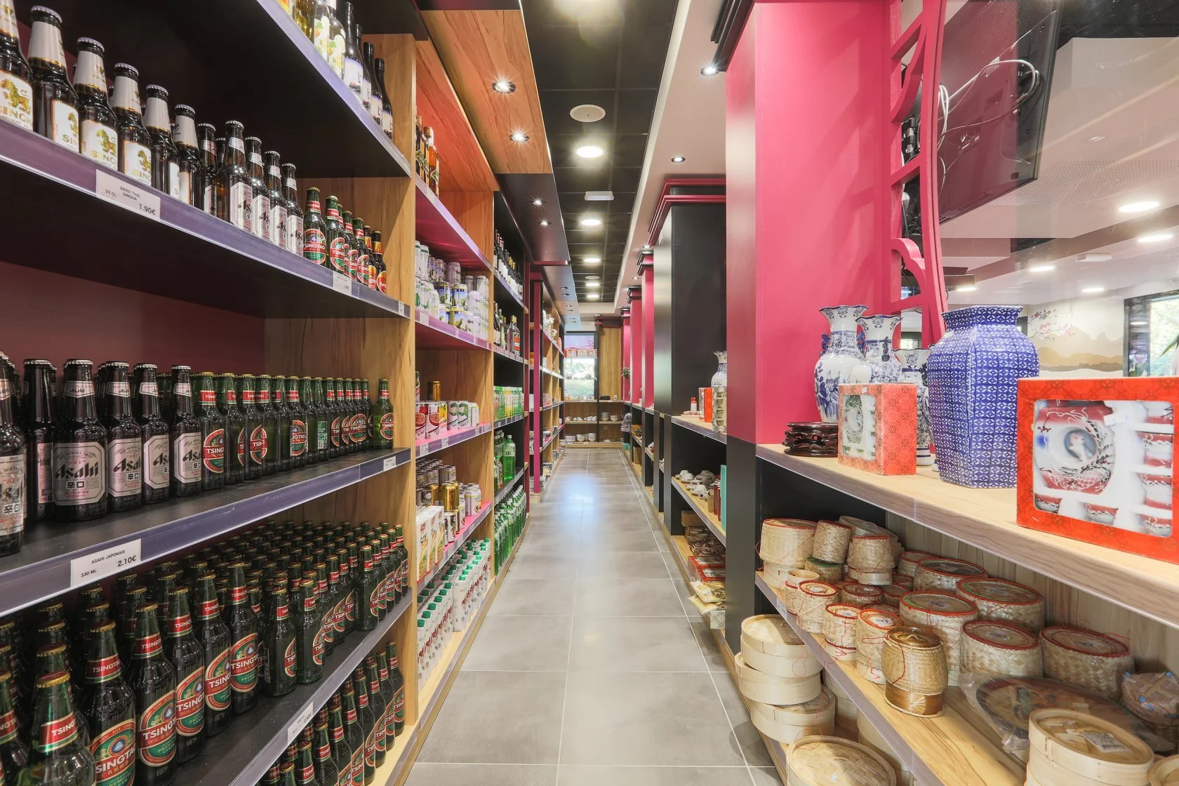 Allée d'épicerie avec des bouteilles de bière sur une étagère et des porcelaines et objets décoratifs chinois sur une autre étagère.