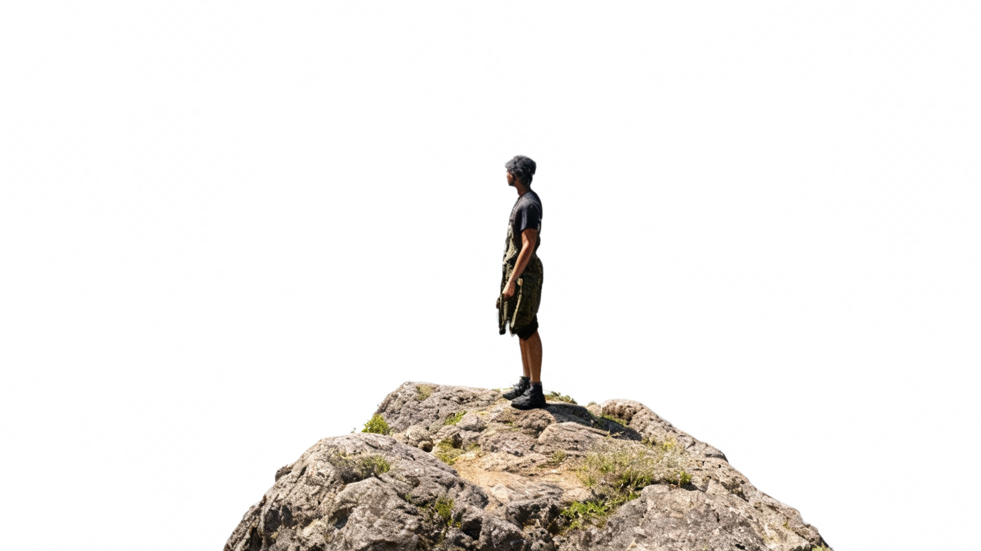 A person standing on a large rock at the top of a mountain, looking into the distance, with a clear sky background.