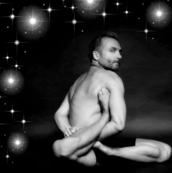 A black and white photo of a man sitting with his back to the camera, his arm flexed, and stars in the background.