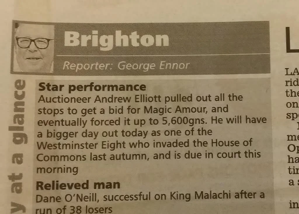 A newspaper clipping with a small photo of a man with glasses in the top left corner. The headline reads 'Brighton' and is followed by a byline 'Reporter: George Ennour'. The article mentions auctioneer Andrew Elliott and his bid for Magic Amour, and a man named Dane O’Neill.