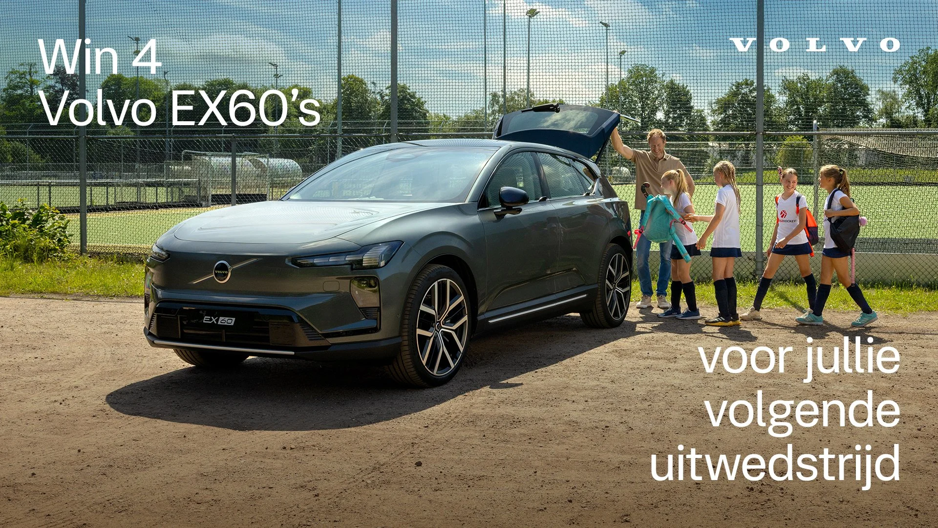Een groepje kinderen en een man staan bij een geopende auto op een tennisbaan, met een hek en bomen op de achtergrond. Tekst op de afbeelding zegt: "Win een rit met 4 Volvo EX60's voor jullie volgende uitwedstrijd."