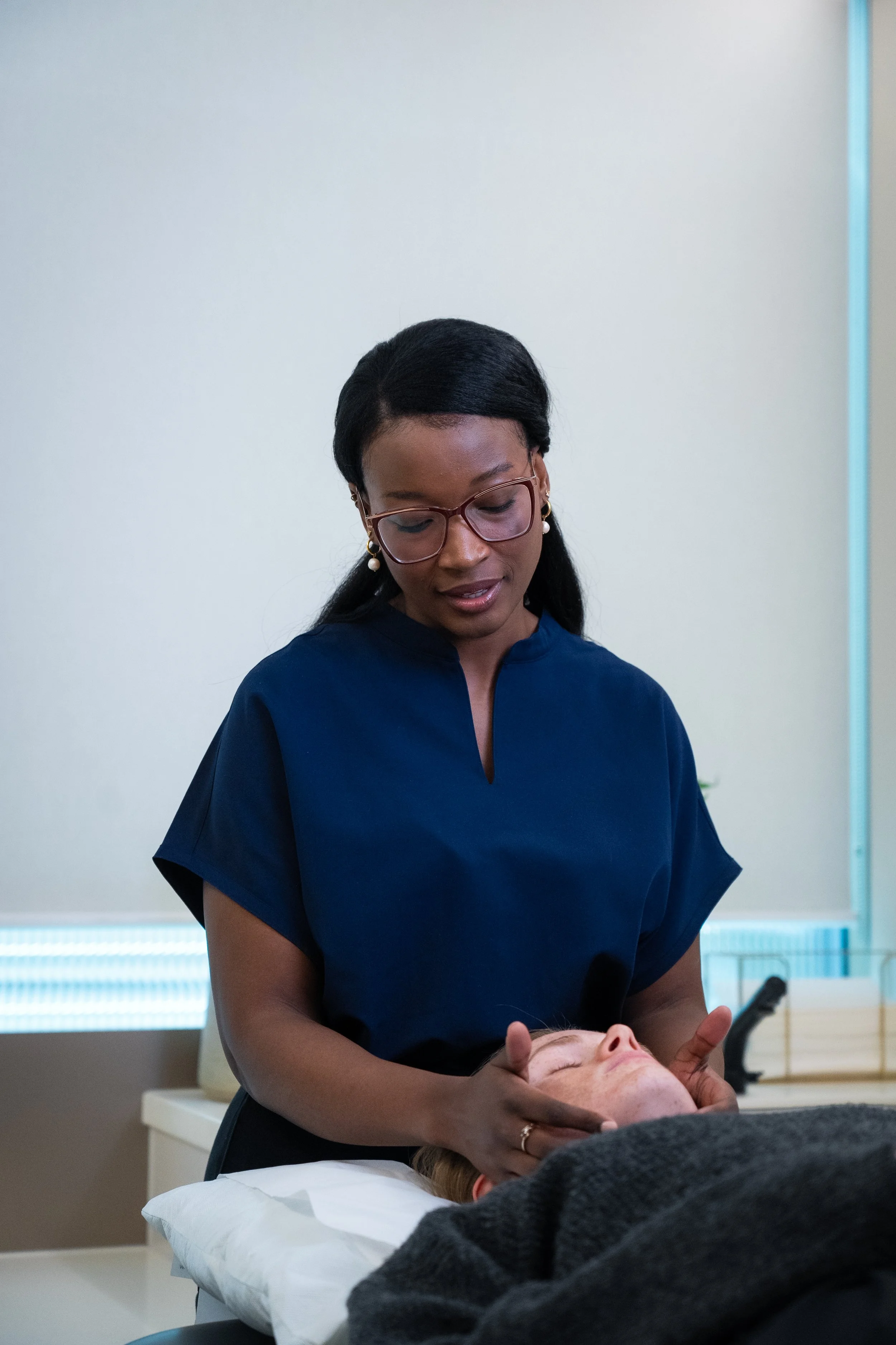 A woman receiving jaw pain treatment from a professional in a clinic setting.