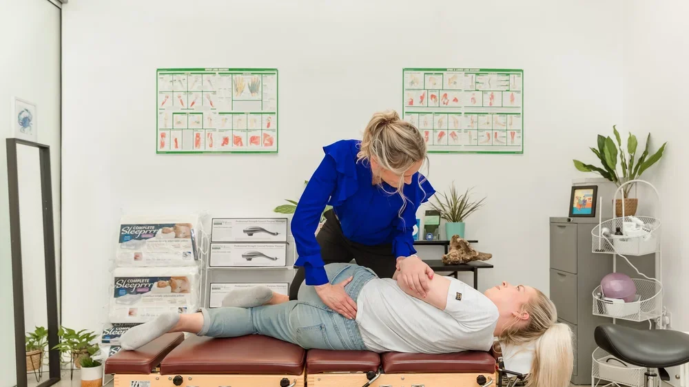 A healthcare professional performing a physical exam on a patient lying on an examination table in a medical office.