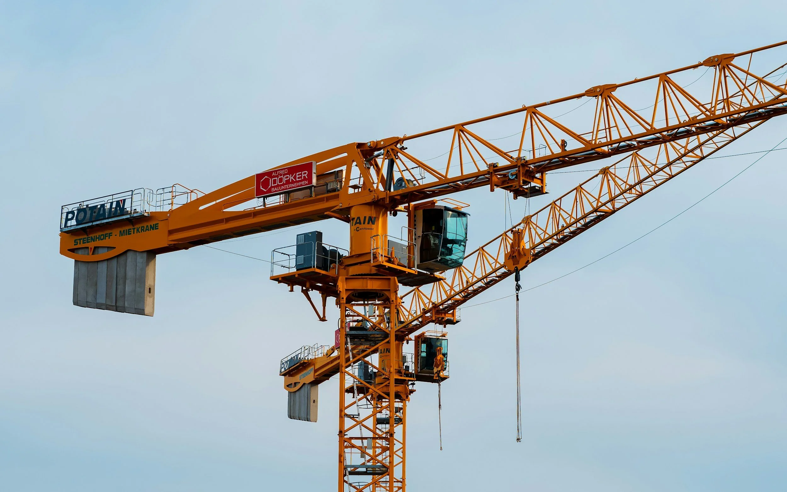 Orange construction crane against a cloudy sky.