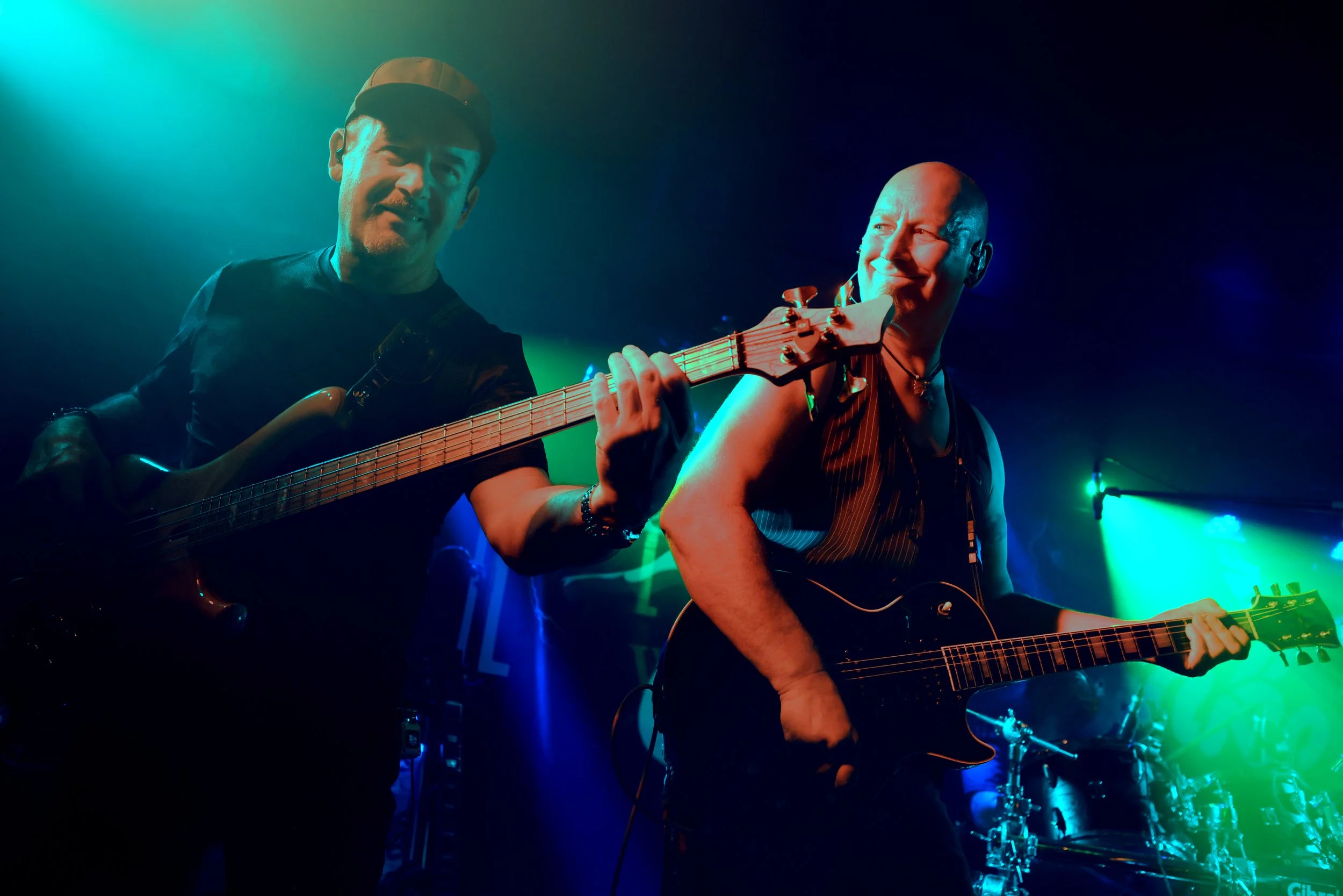 Two musicians performing on a stage with colourful lighting.