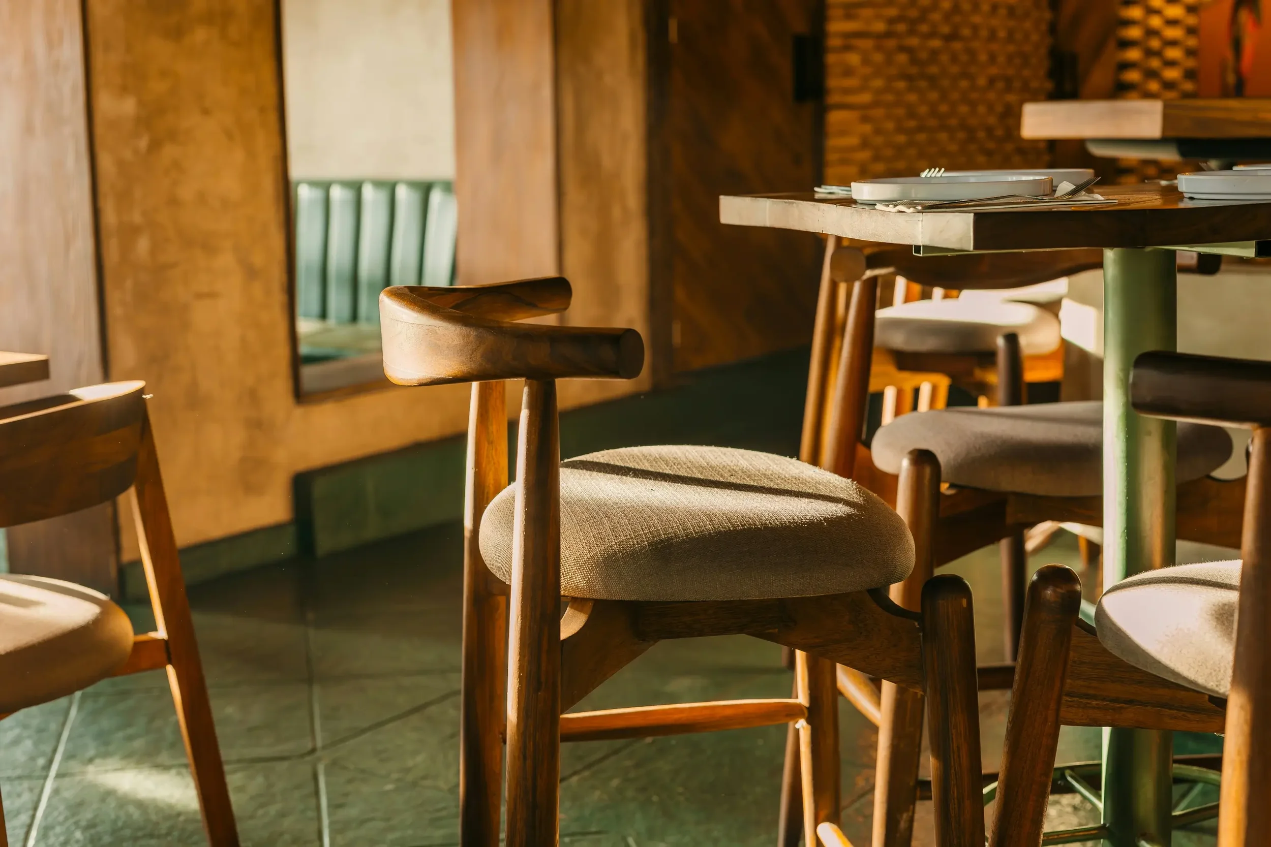 Empty wooden table and chairs in a warmly lit restaurant or cafe with sunlight filtering through.