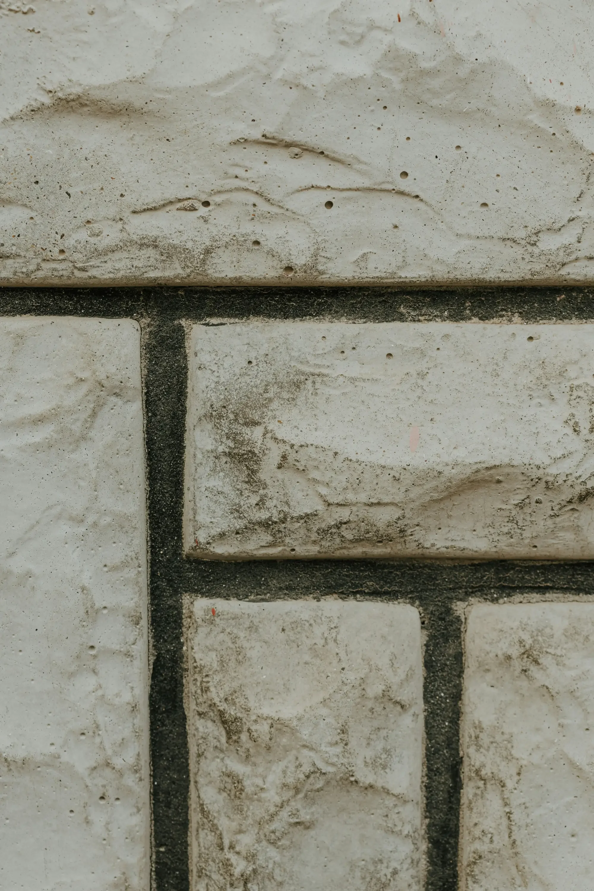 Close-up of a white brick wall with dark mortar lines, showing weathered and textured surface.