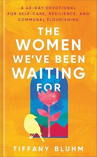 Book cover titled 'The Women We've Been Waiting For' by Tiffany Bluhm, with a background in shades of orange, featuring a stylized illustration of a woman with a yellow hood and a pinkflower inside a blue rectangular frame.
