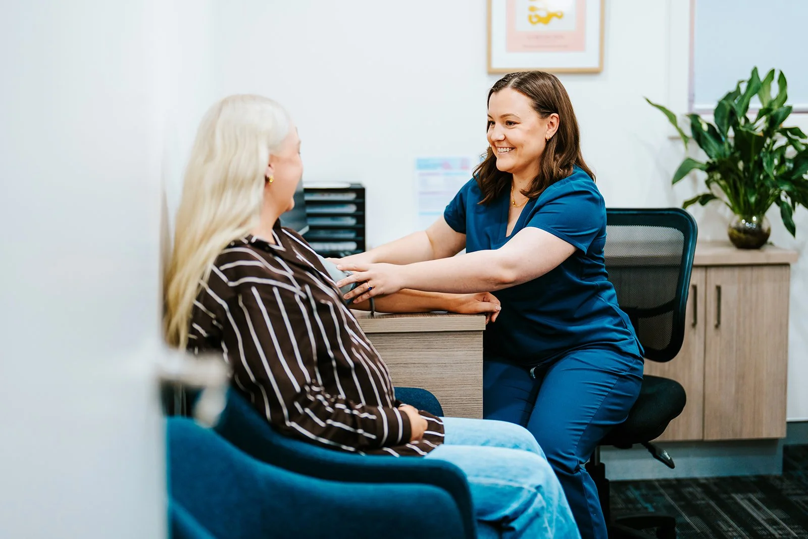 A healthcare professional performs an assessment on a woman in a medical office.