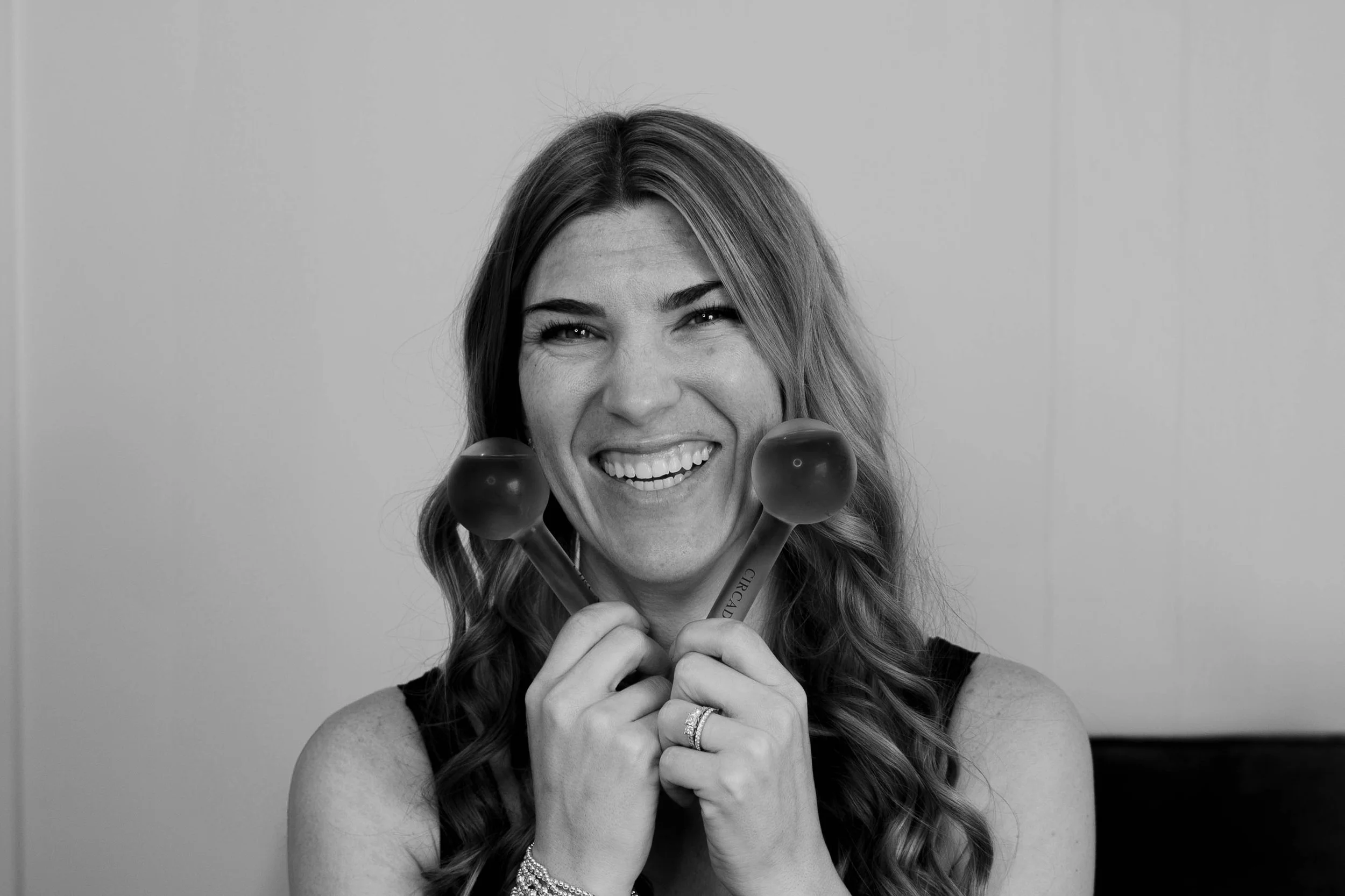 Black and white photo of Brittany Phalen of Illuminate Lashes and Beauty in Trussville Alabama smiling and cooling globes near her face.