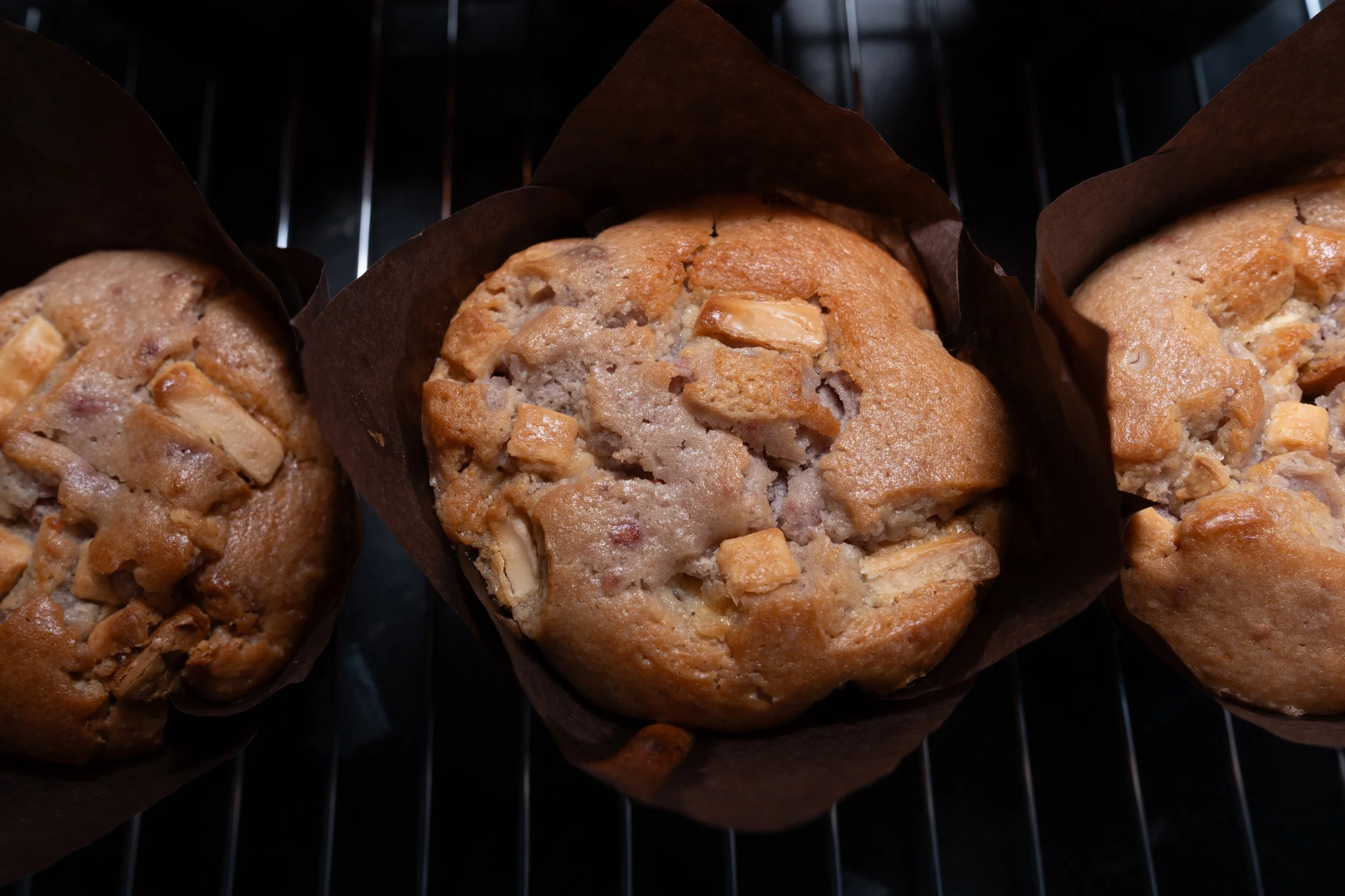 Close-up of three banana nut muffins in paper baking cups on a wire rack.