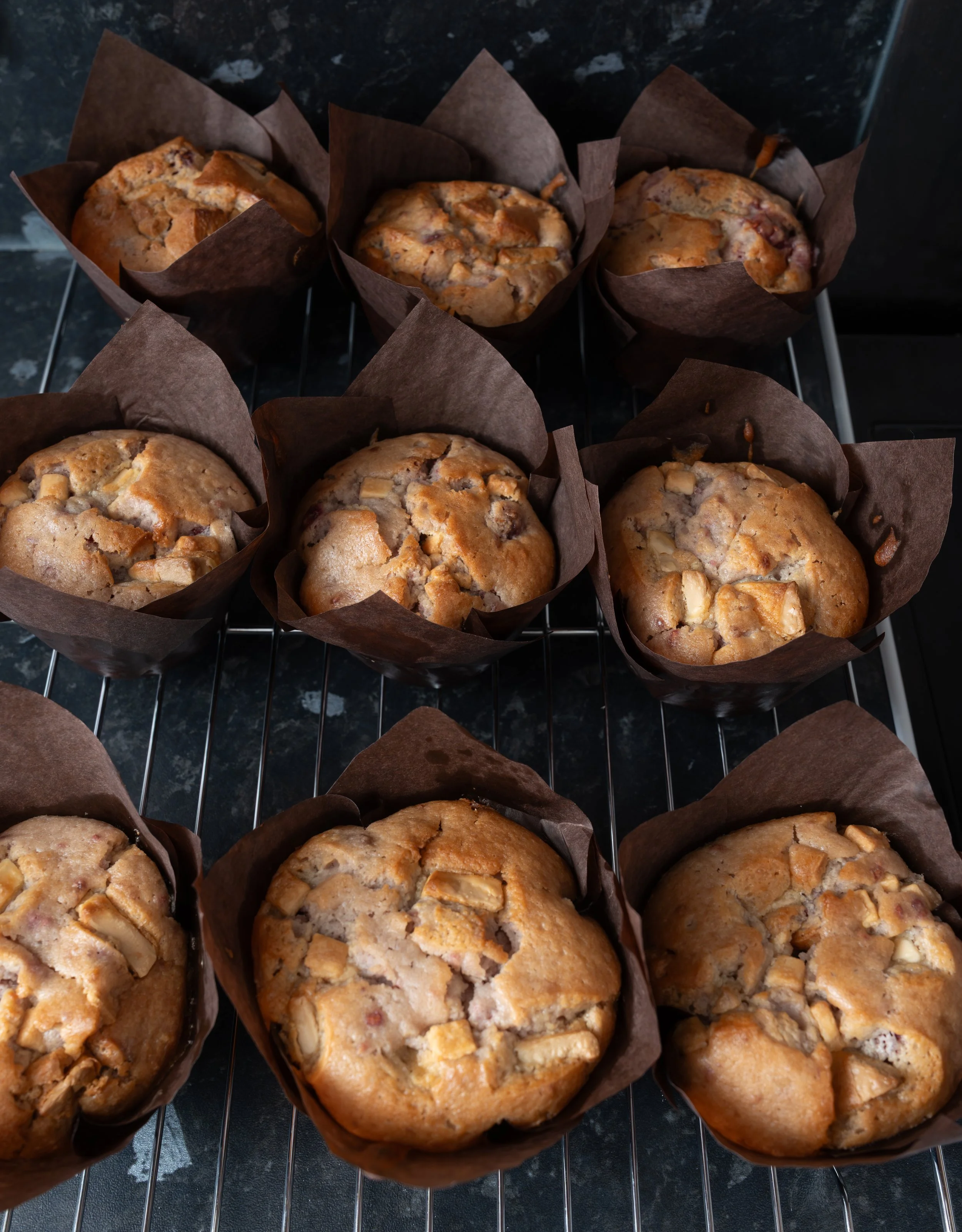 A tray of freshly baked muffins with nuts, sitting on a cooling rack.
